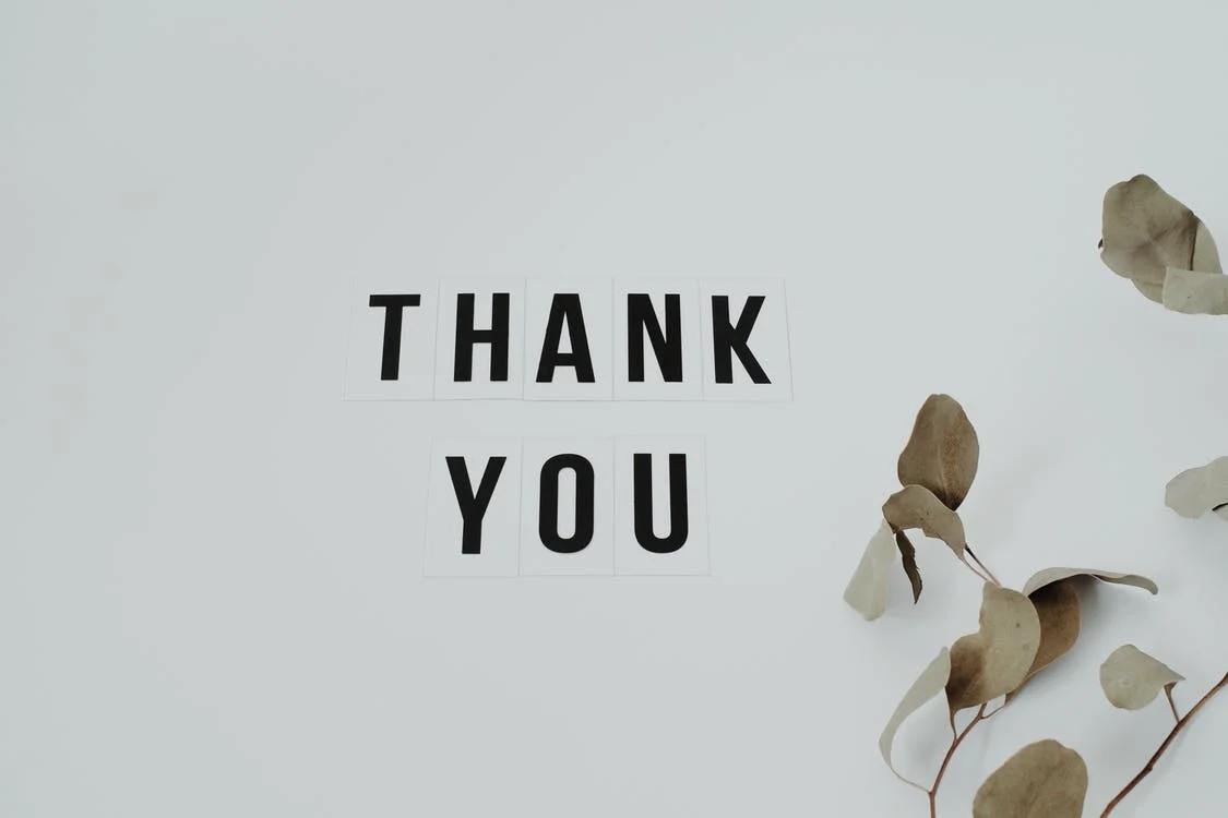 An image showing thank you in black text and some leaves on the right