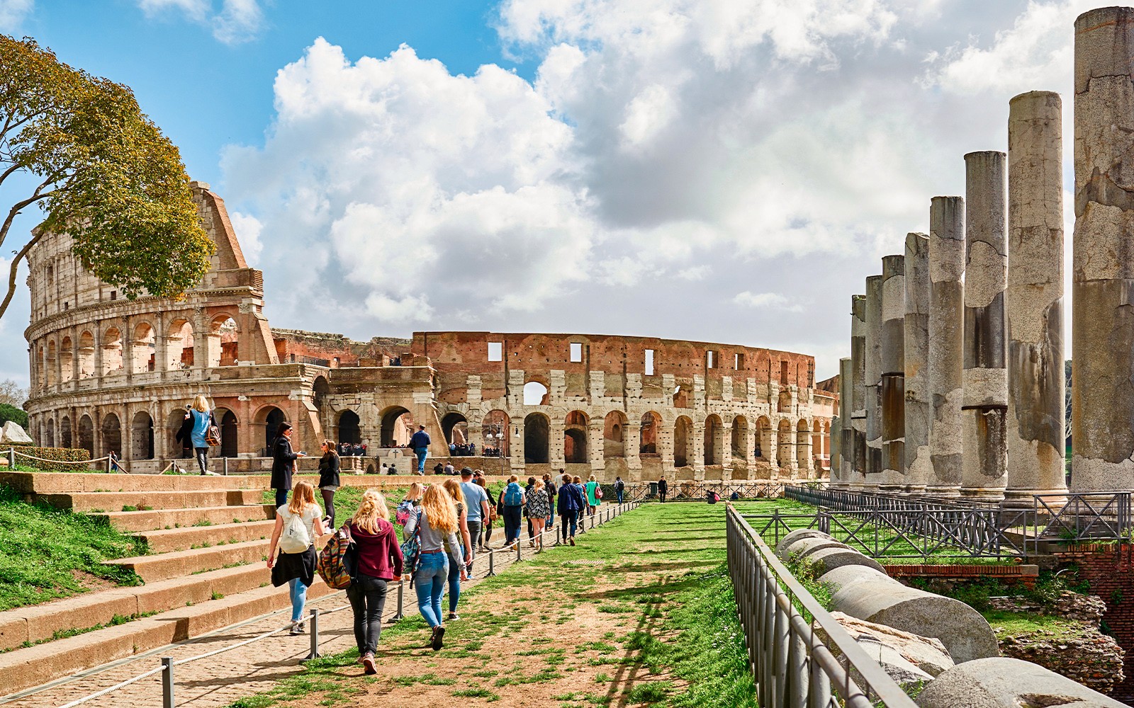 在罗马斗兽场附近漫步的游客，可以看到古老的柱子。