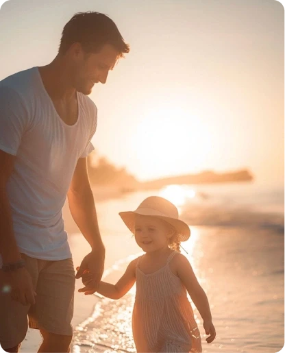 Father and daughter walking on beach at sunset