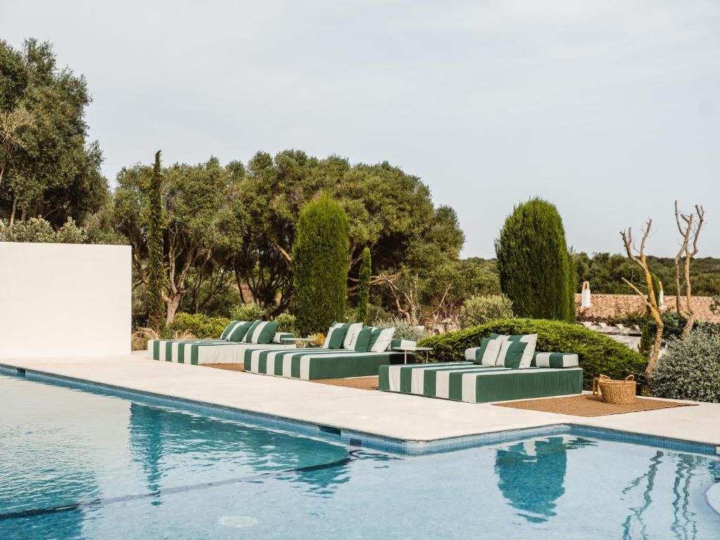 Outdoor restaurant terrace overlooking a tranquil lake at sunset. White tables and chairs are set with glassware. Sheer curtains add elegance. Calm ambiance.