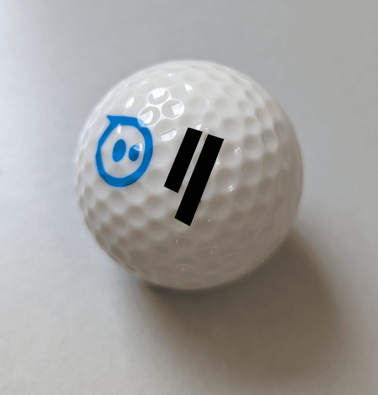Close-up of a white sphero robot printed with the Qubic logo on a clean white background.