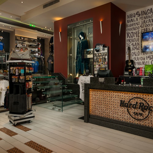Hard Rock Café 商店内部,陈列着各类周边商品,有一个展示蓝色服装的陈列柜和一个接待柜台。
