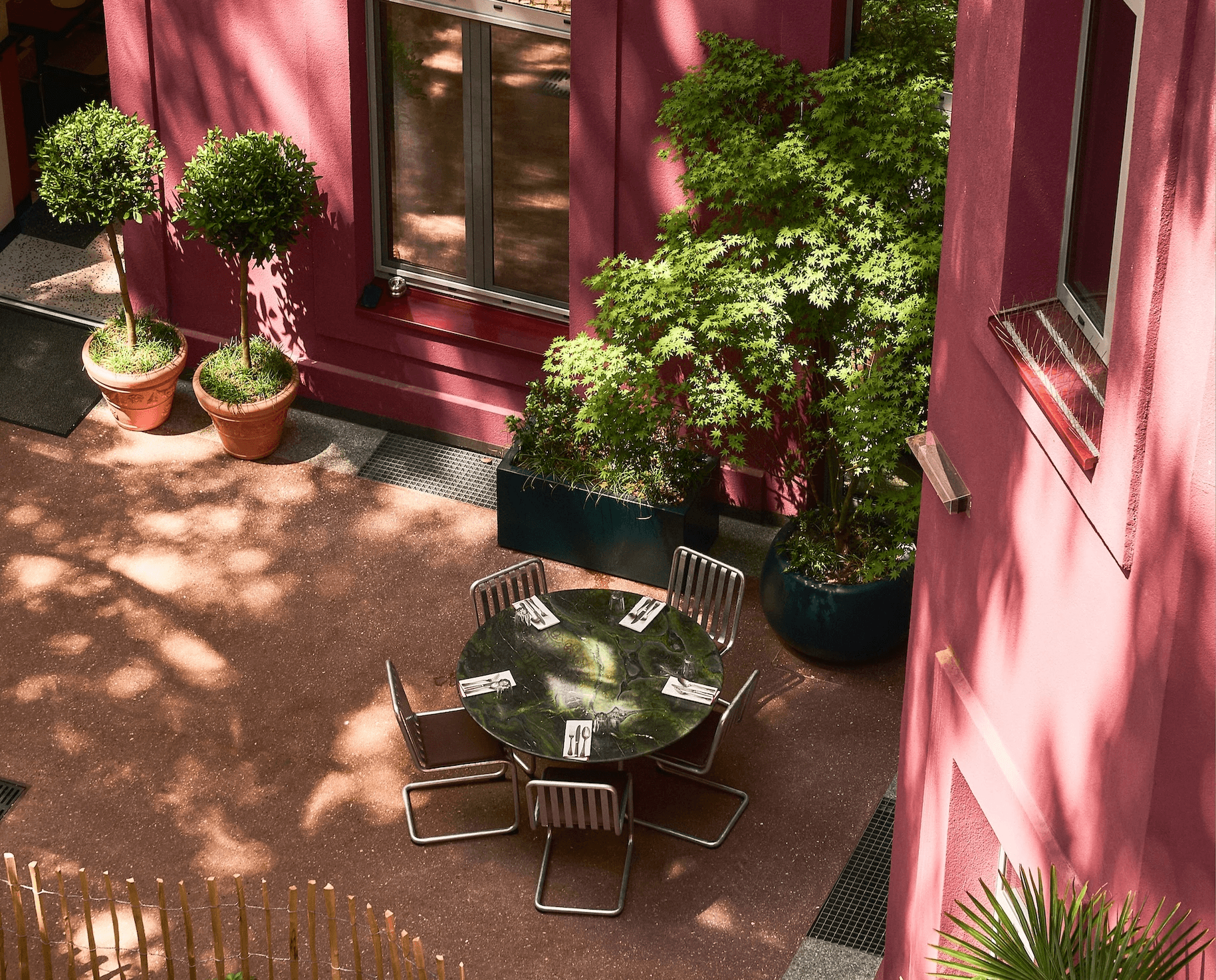 Boca courtyard viewed from above with garden beds, tree shade, and outdoor tables