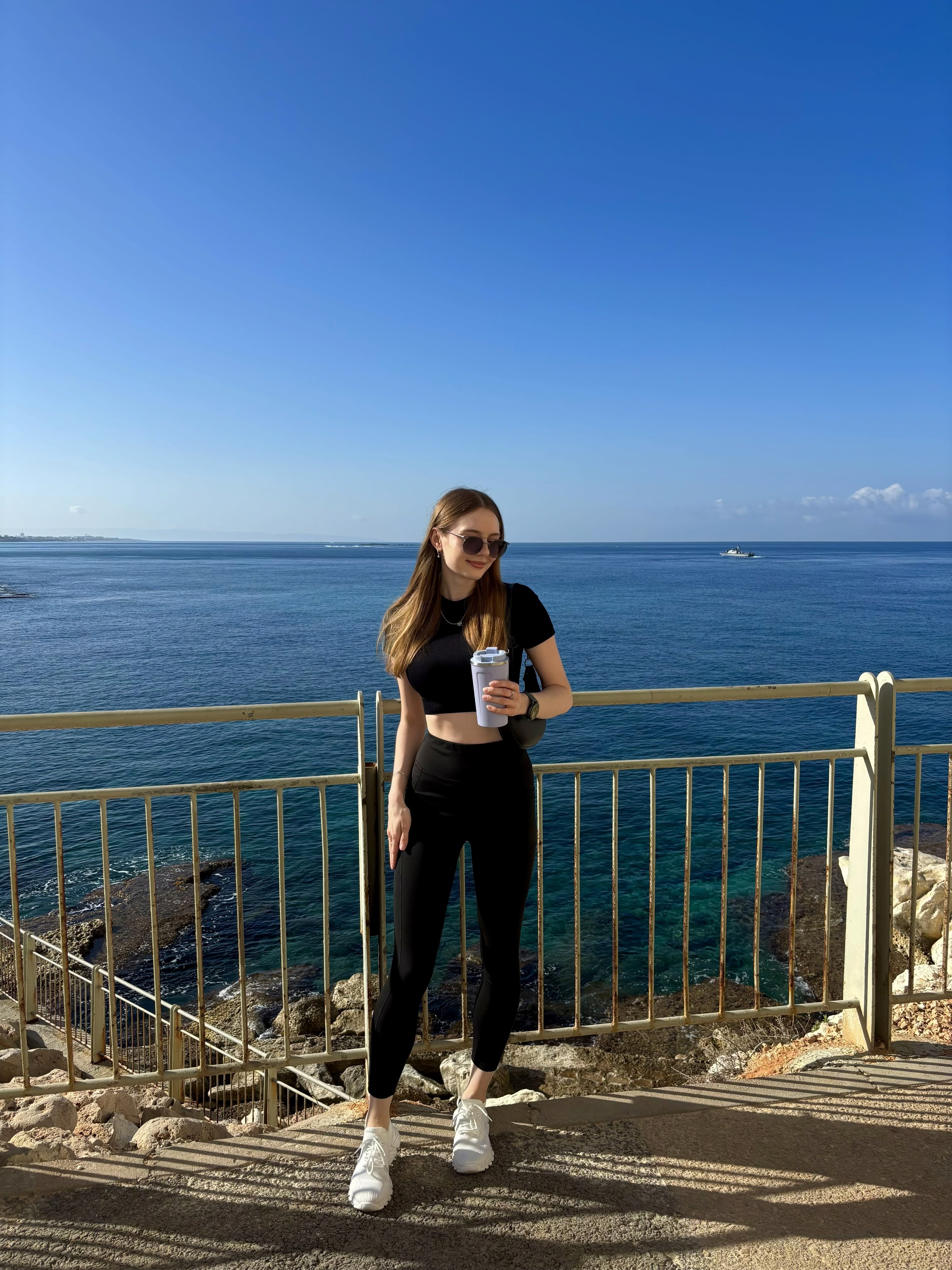 Liana Tudakova — founder of Luna UI Design Studio, standing by the Mediterranean Sea on a sunny day, symbolizing clarity, calm, and the global vision behind her design philosophy.