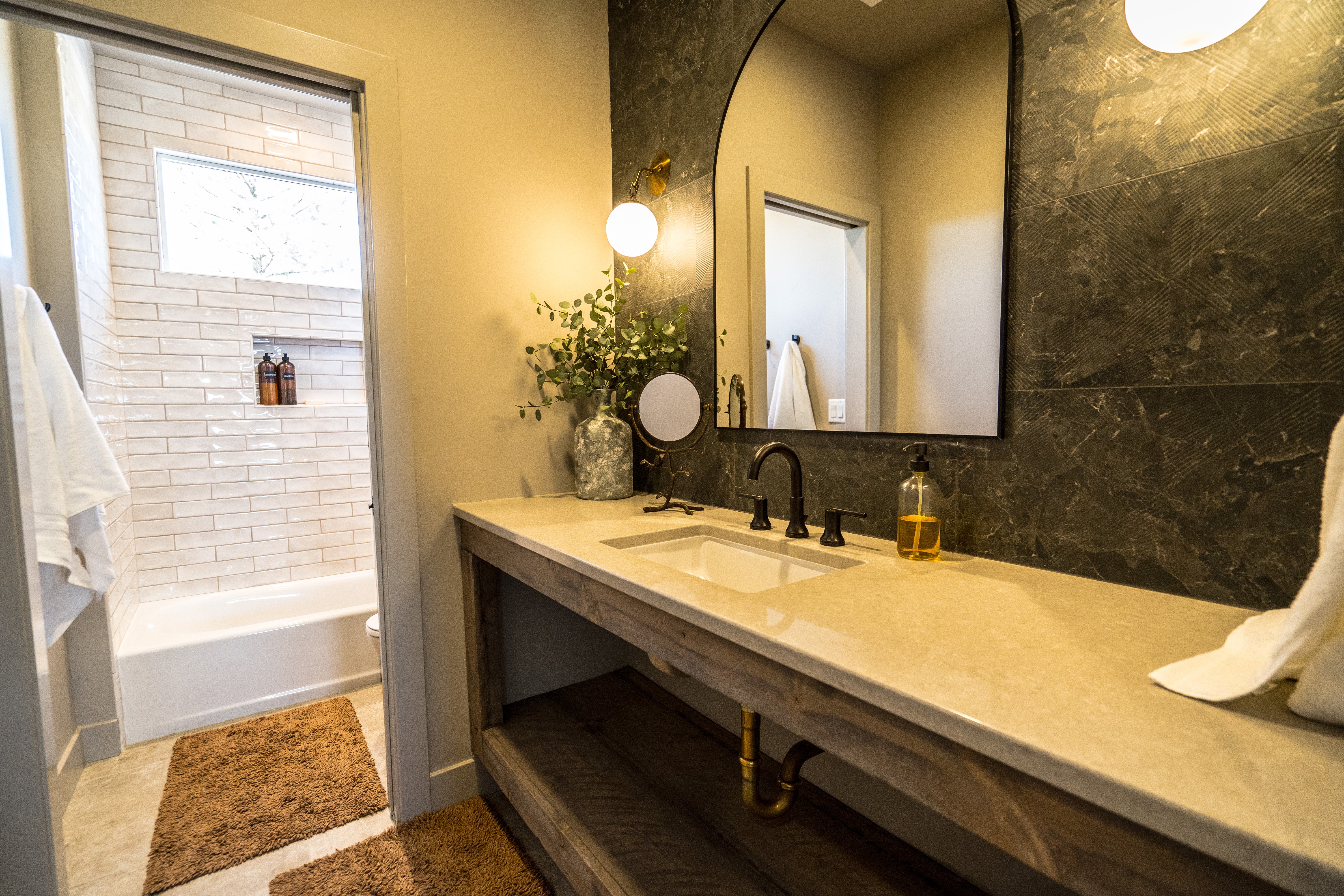 Custom bathroom in a Hurricane, Utah twin home with a floating cabinet, quartz countertop, pony wall, euro glass, full tiled shower.