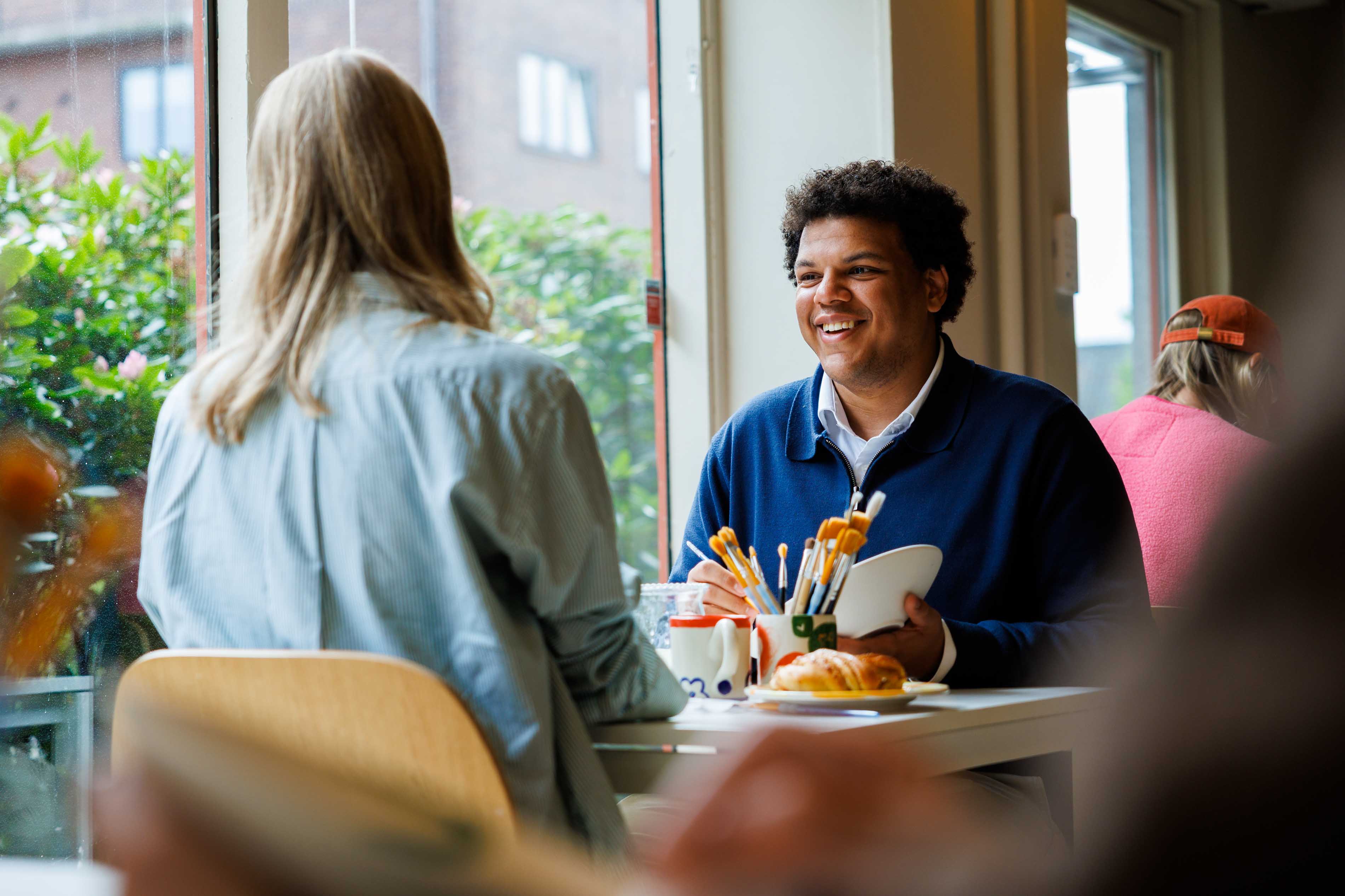 Par som sitter ved et bord og maler på keramikk