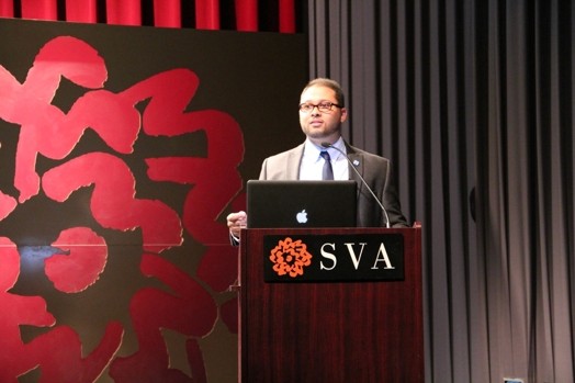a man giving a speech from a stand in the "designer as" thesis presentation