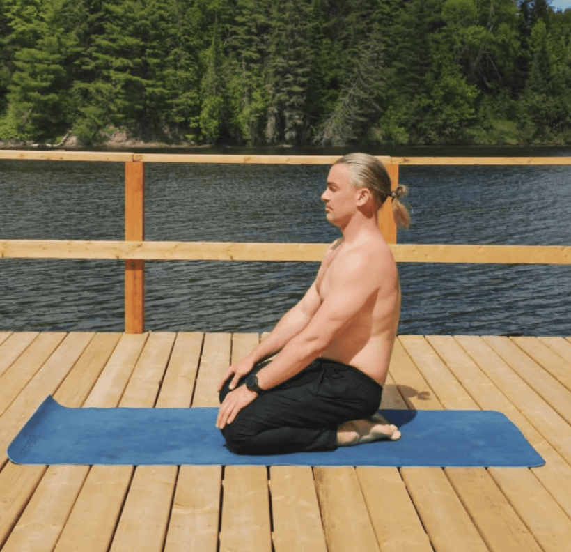 Personne en posture de yoga assise sur un tapis sur un quai en bois