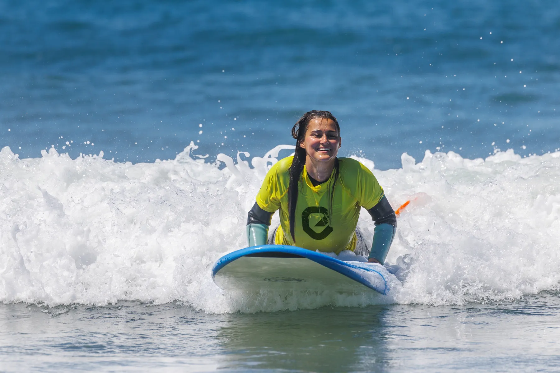 Surfista sonriente montando una ola durante una clase para principiantes en Tarifa. Disfruta la mejor experiencia de surf y alojamiento en la playa con Explora Watersports.