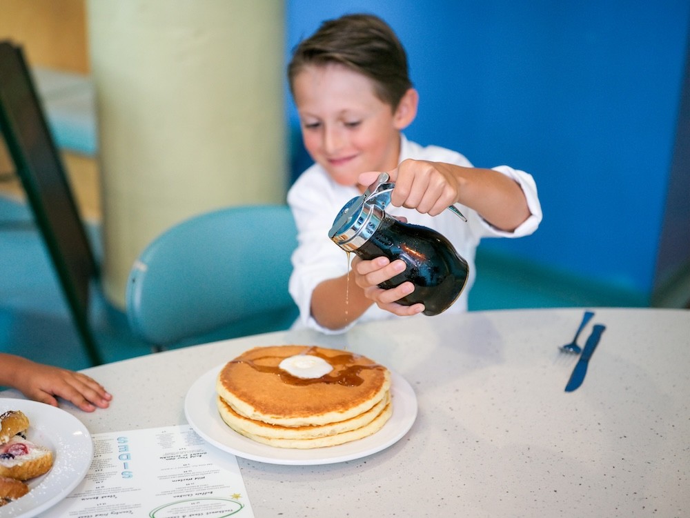 Kid pouring syrup at Wild Eggs