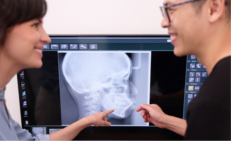 A dentist and patient reviewing a dental x-ray on screen