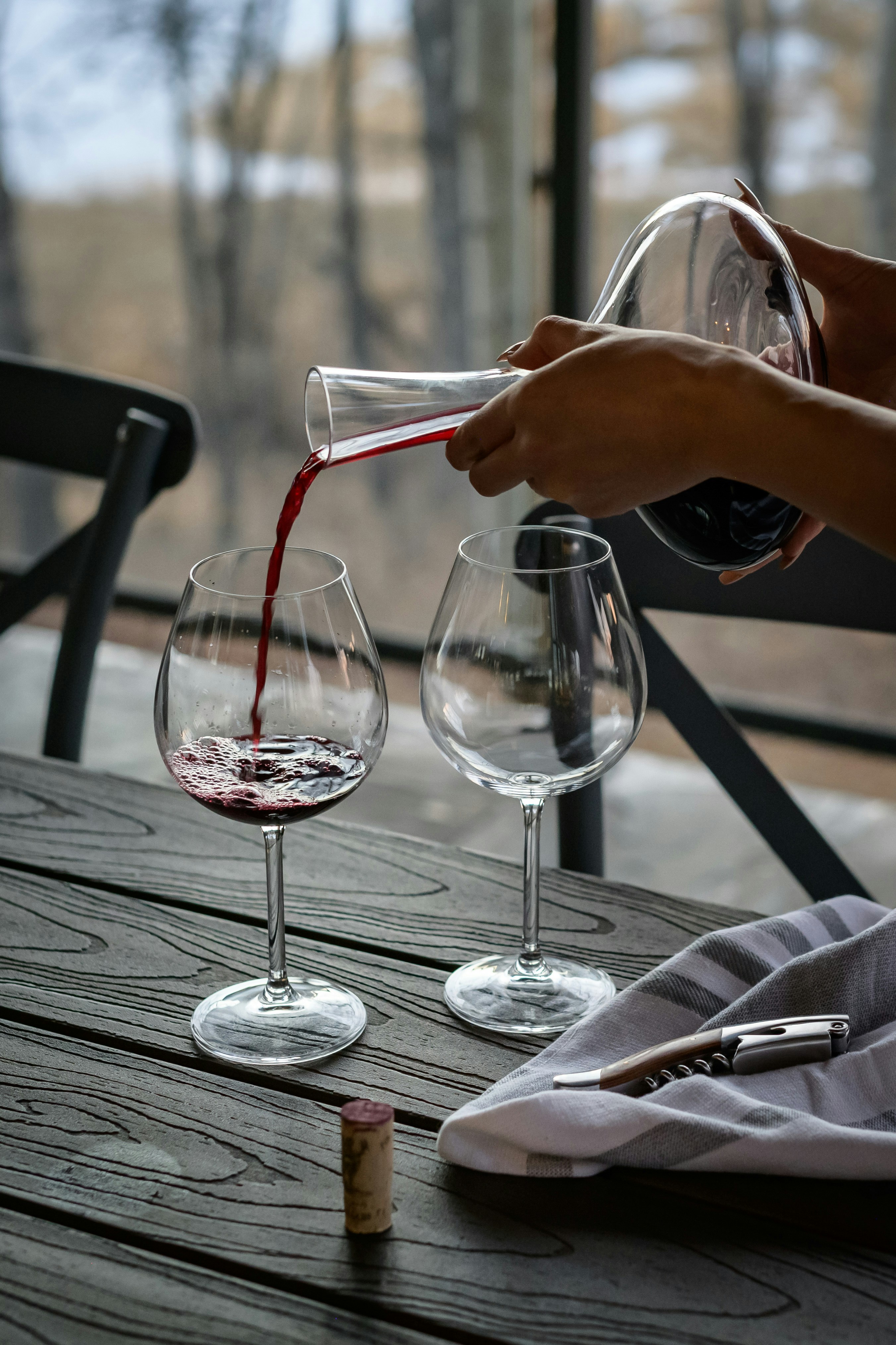 White woman pouring red wine from decanter to glass