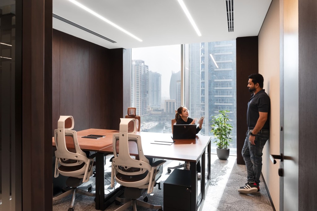 Elegant serviced offices reception with marble desk, iMacs, and vertical wood slats.