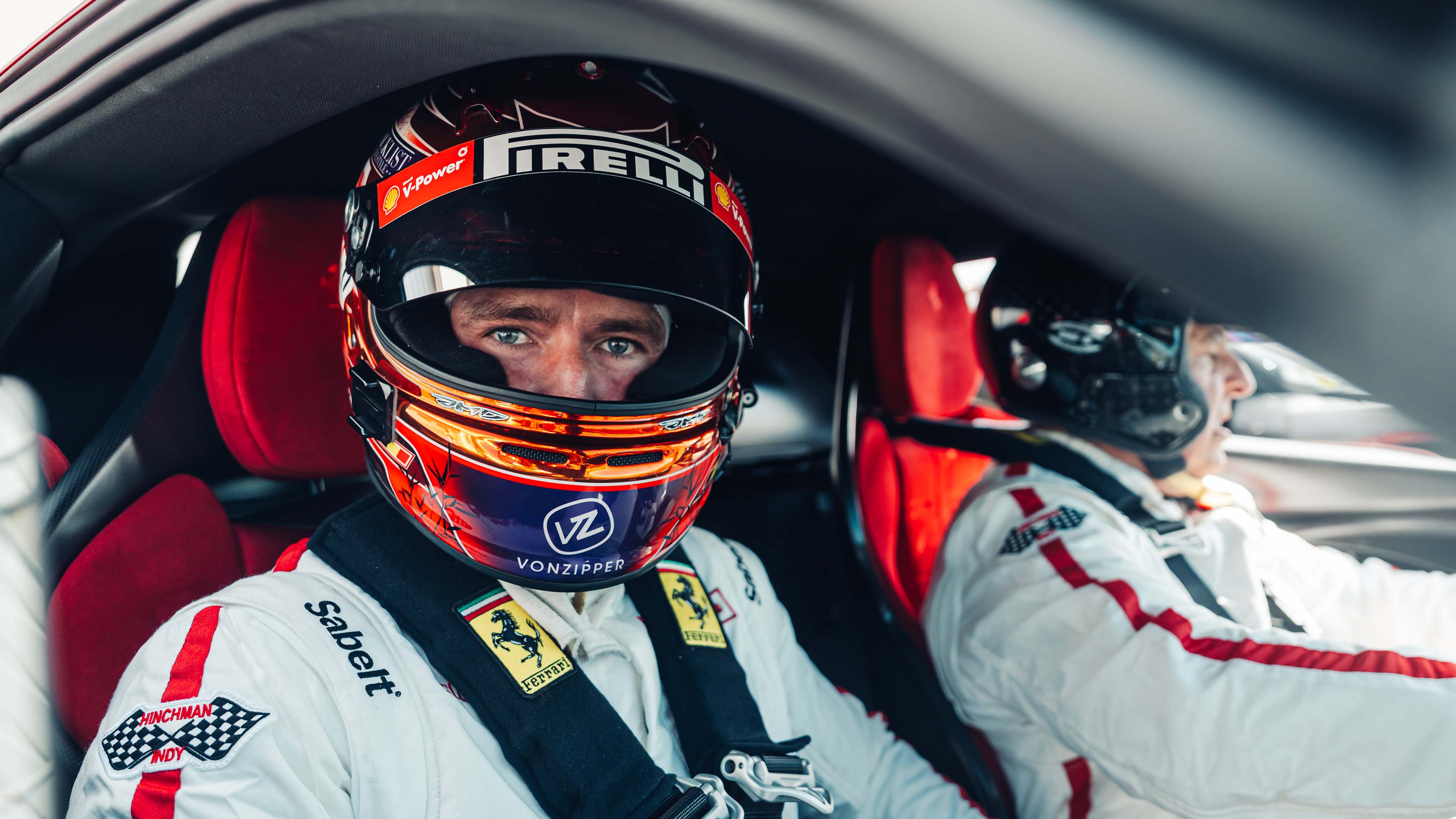 Foto di pilota con casco e tuta a bordo di Ferrari