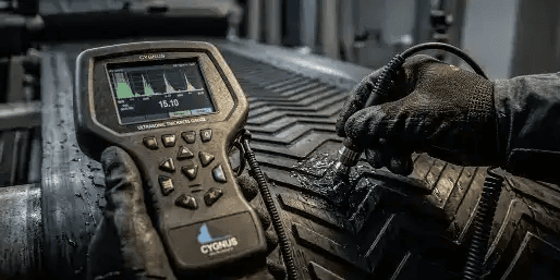 Glospech technician using Cygnus 1 EX intrinsically safe ultrasonic thickness gauge to measure wall thickness through rubber lagging on mining conveyor pulley
