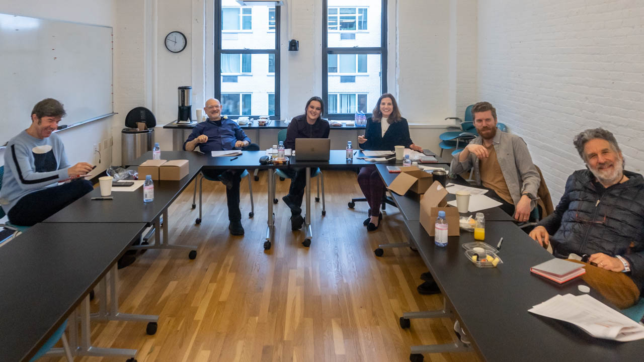 group photo of six people sitting at desks in a classroom