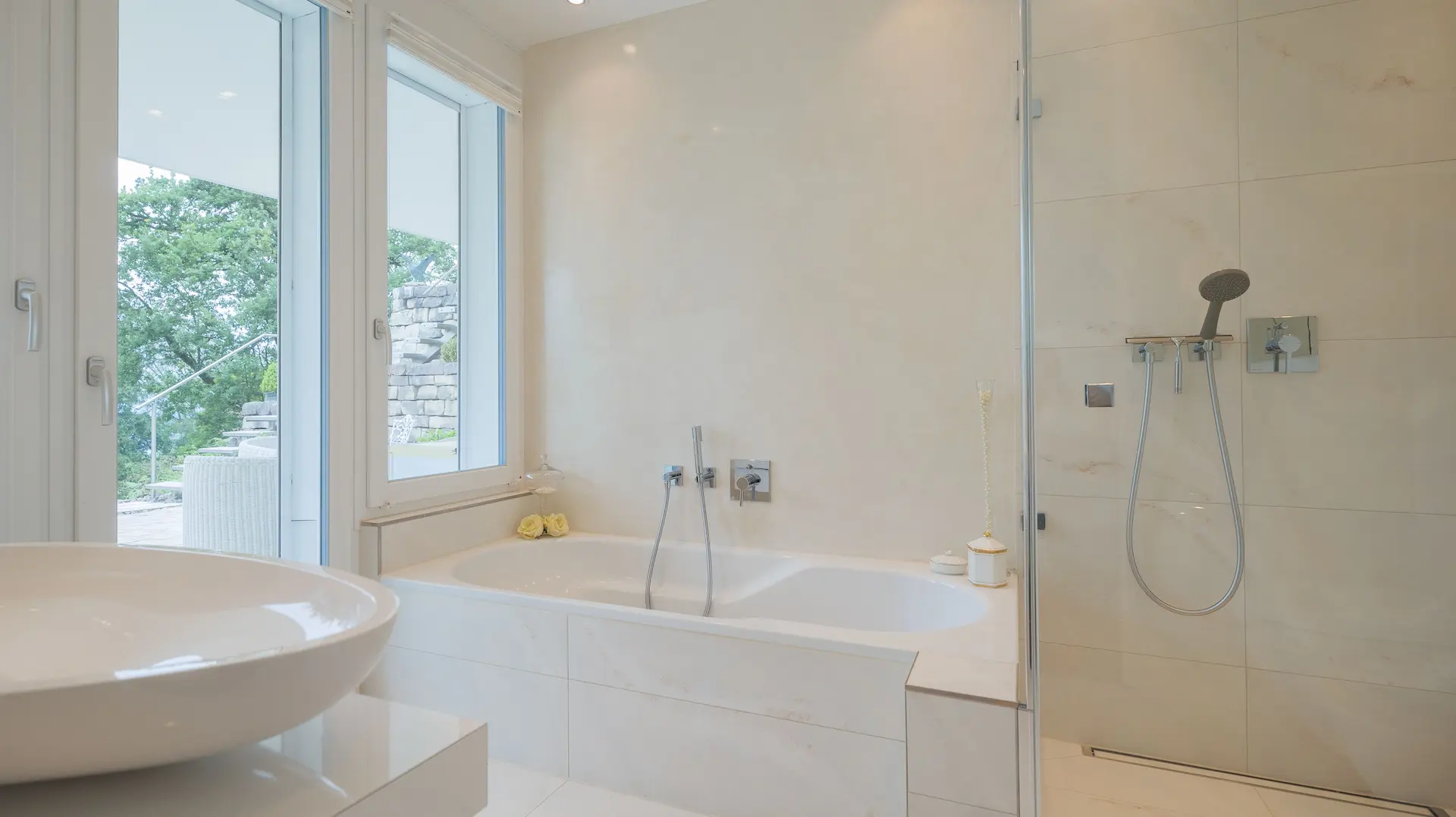 Helles Badezimmer mit Badewanne, Dusche und Zugang zum Aussenbereich