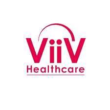 A young woman with long brown hair smiles warmly against a green background, dressed in a black jacket and white shirt.