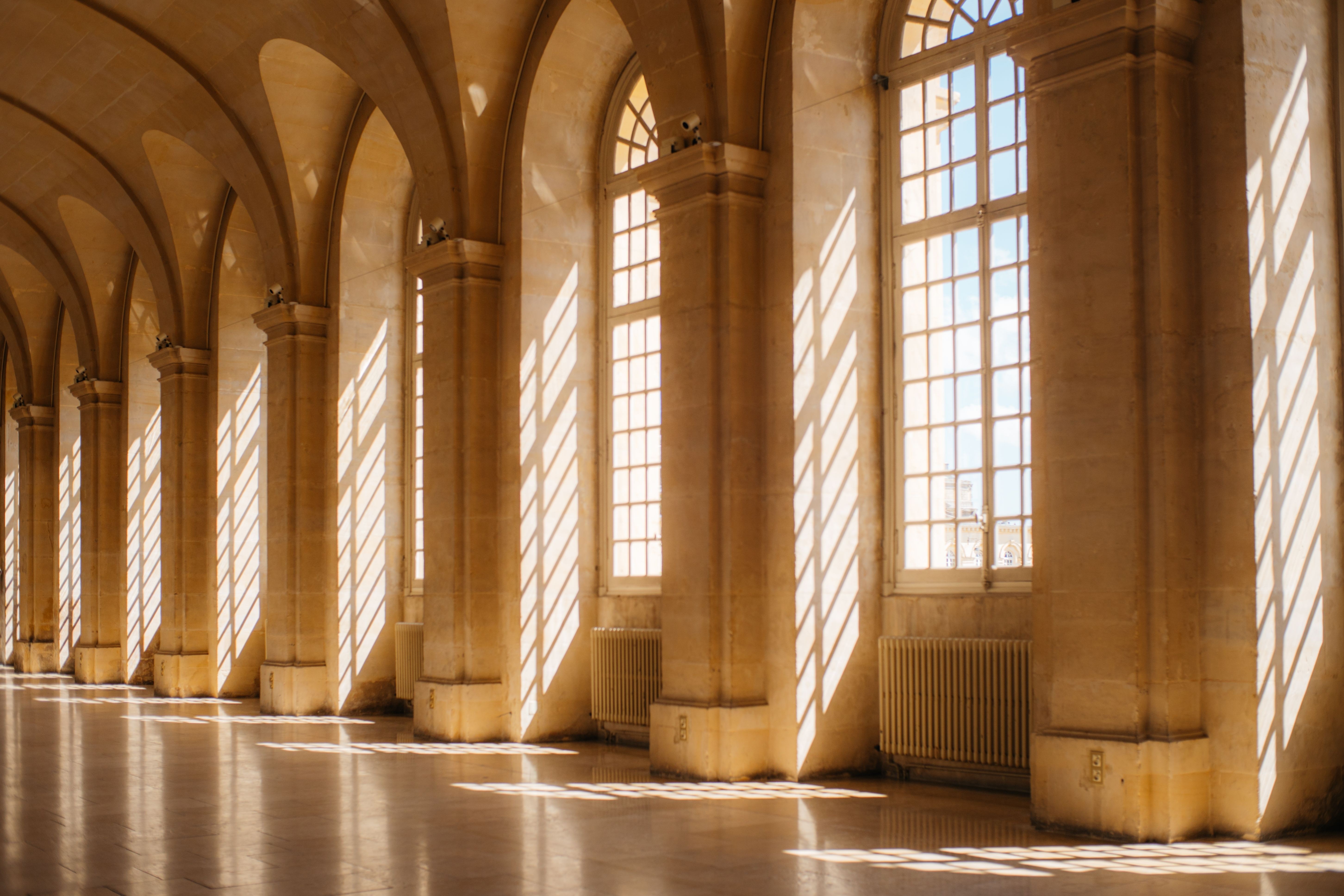 A classical hallway with tall arched windows and soft sunlight, representing clarity, structure, and fiduciary purpose.