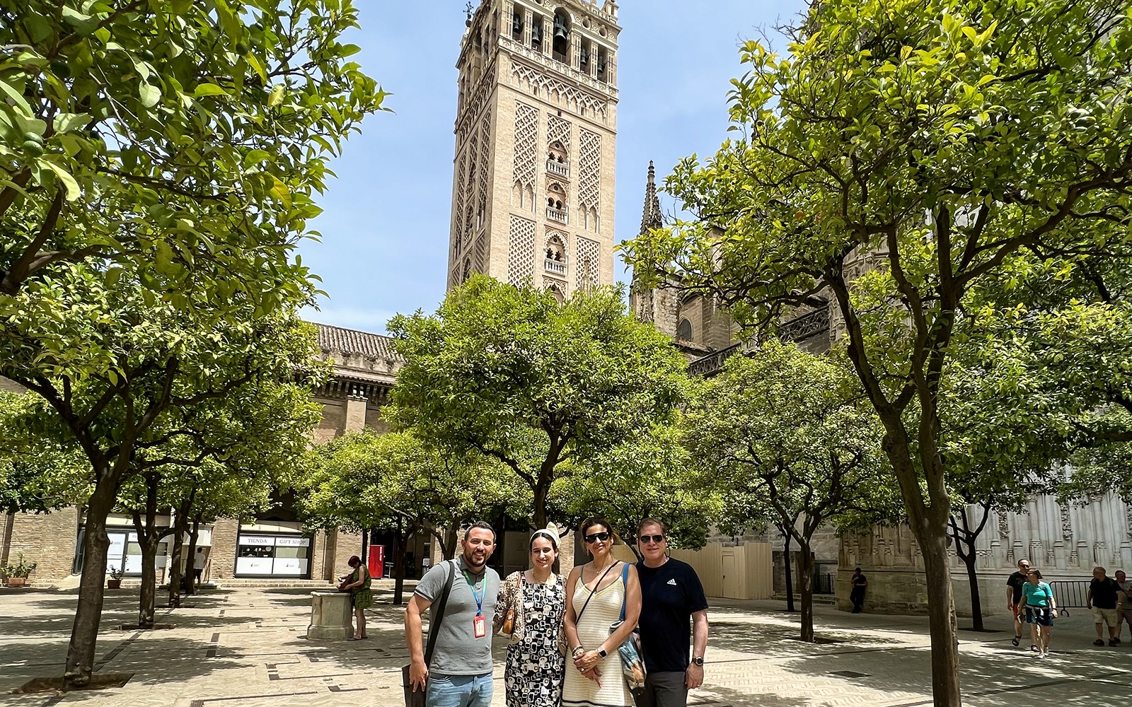 Visitors in courtyard with view of Giralda Tower, Seville, during guided tour.