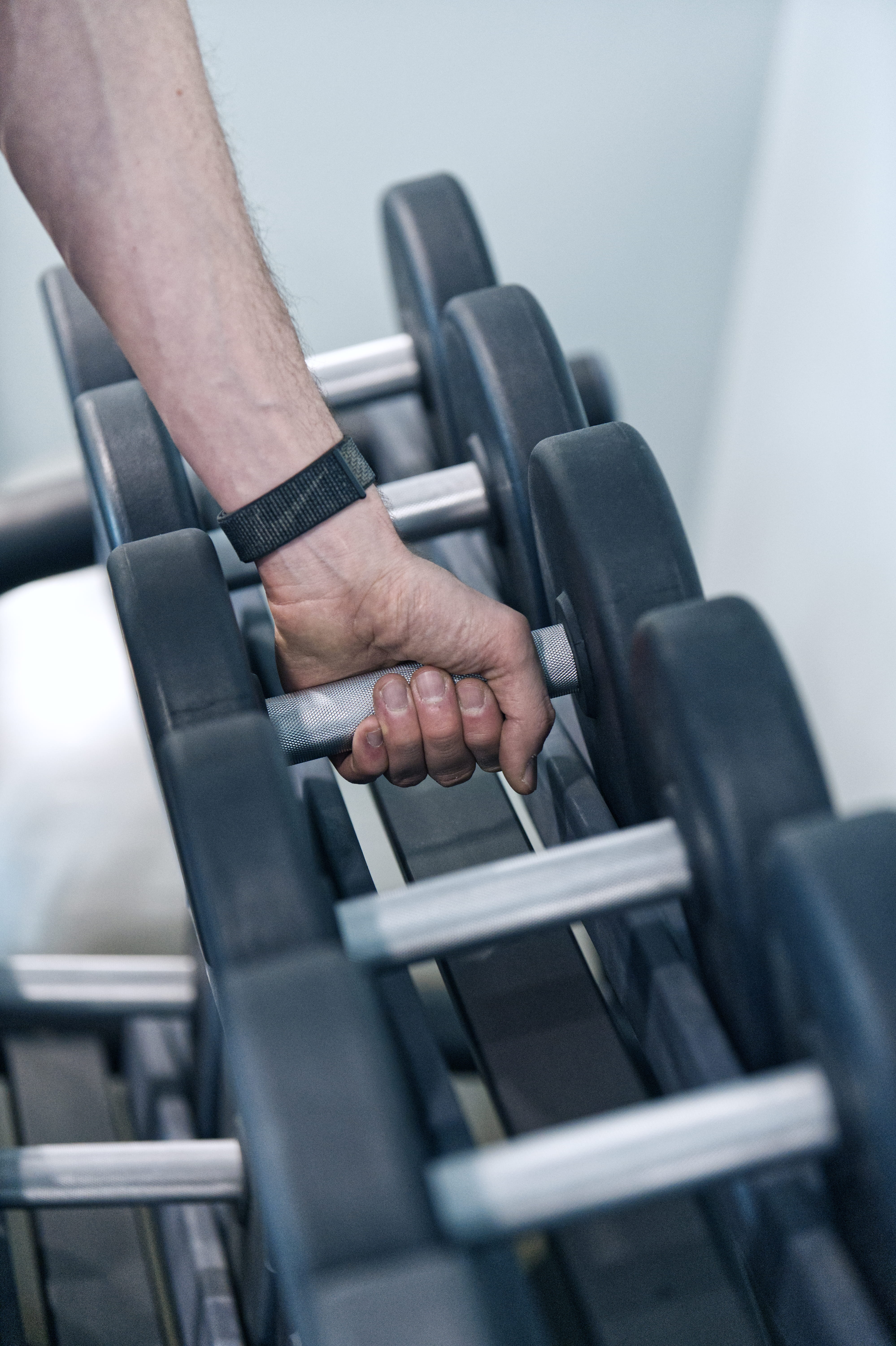 Two people sit at a white table in a dimly lit room, discussing something. The man gestures towards a laptop, while the woman listens attentively.