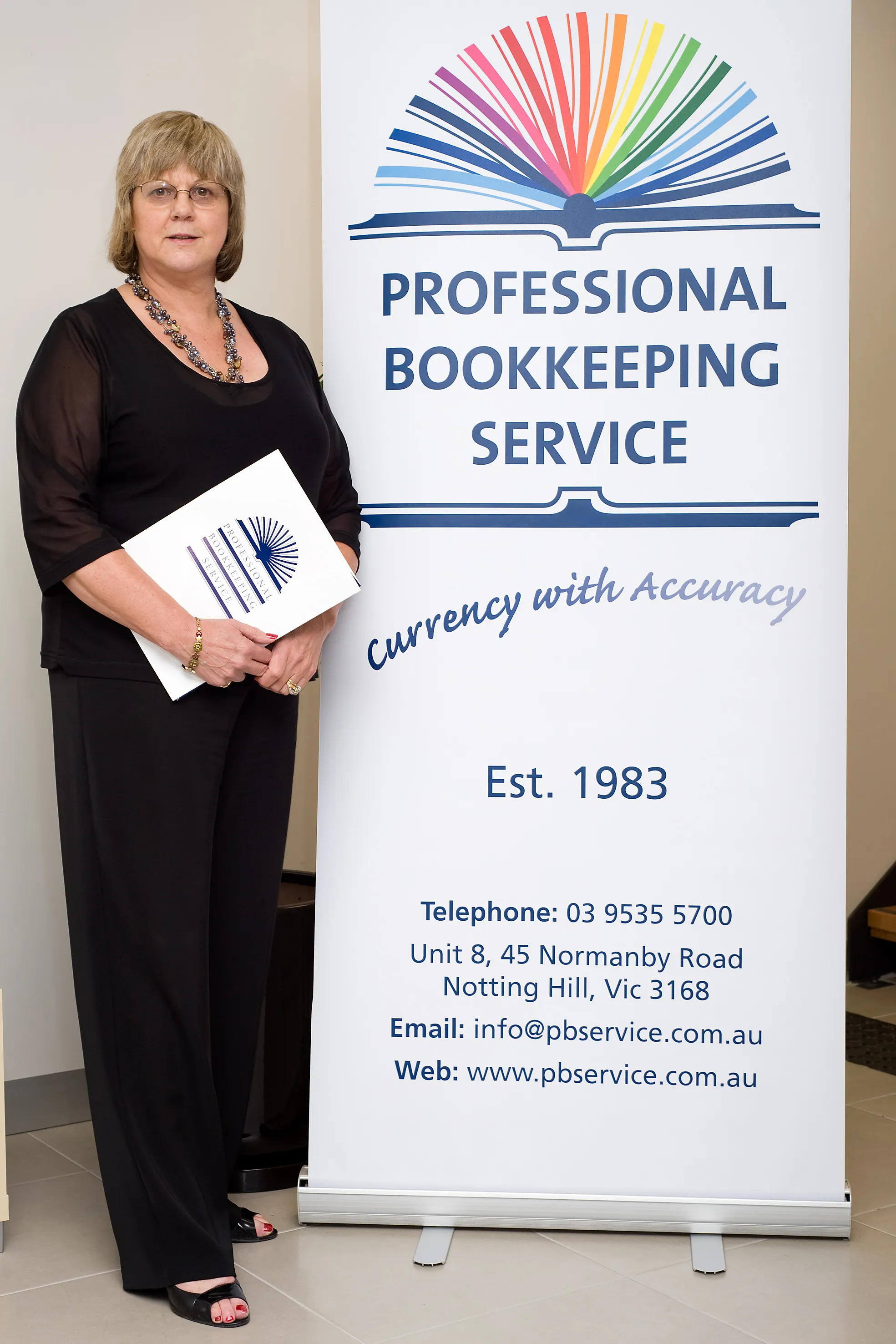 Helen Stenhouse standing beside a Professional Bookkeeping Service banner.