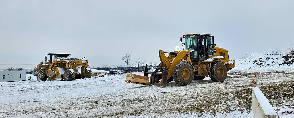 Wheel loader and motor grader parked on a snow-covered job site
