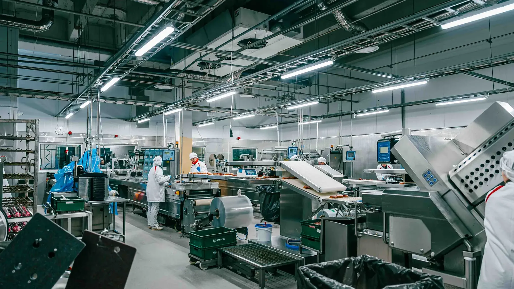 Workers in hairnets and uniforms operating packaging machinery in a production hall