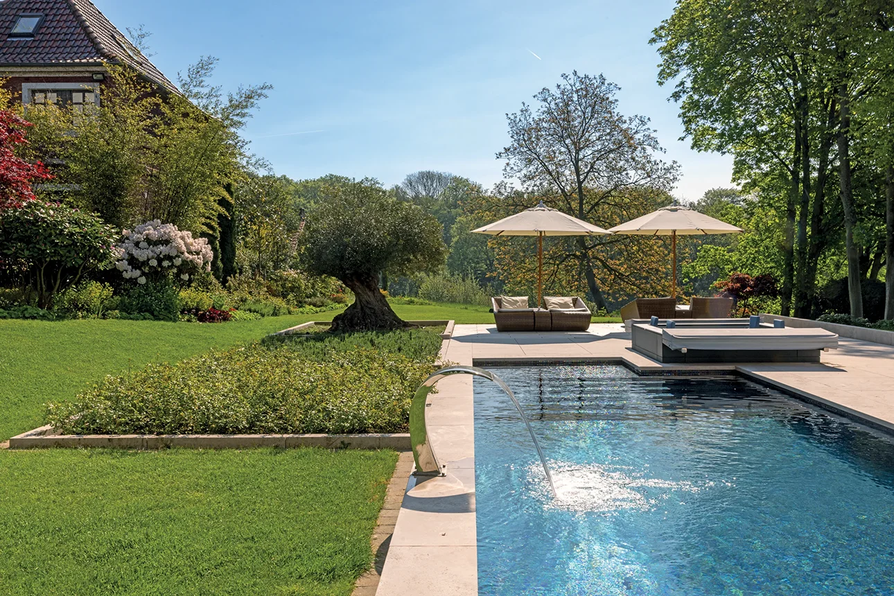 Üppige Gartenanlage mit Poolrand, Liegestühlen und Sonnenschirmen