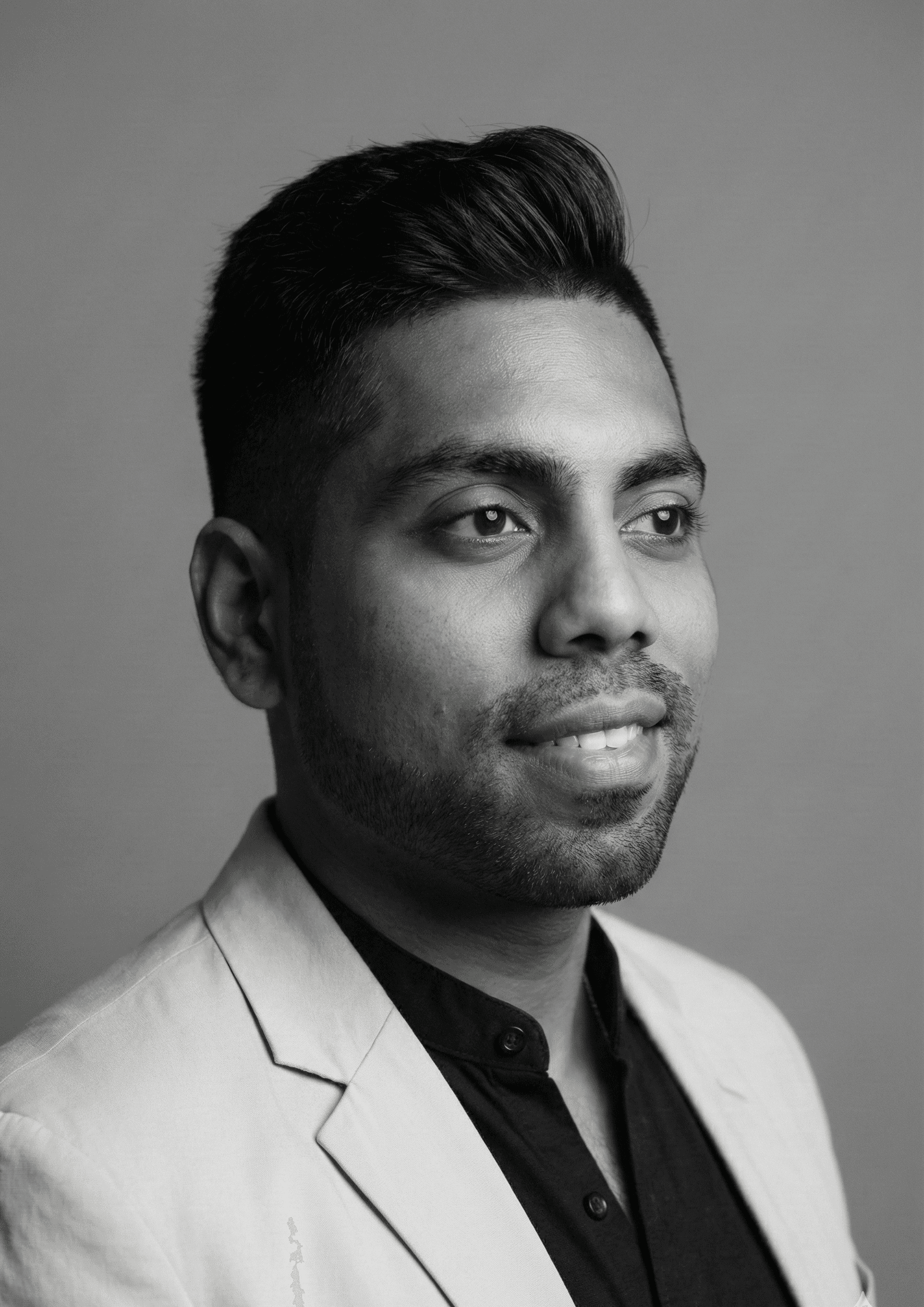 Portrait of a woman with long, smooth hair swept to the side, in a dark t-shirt, on a plain background.