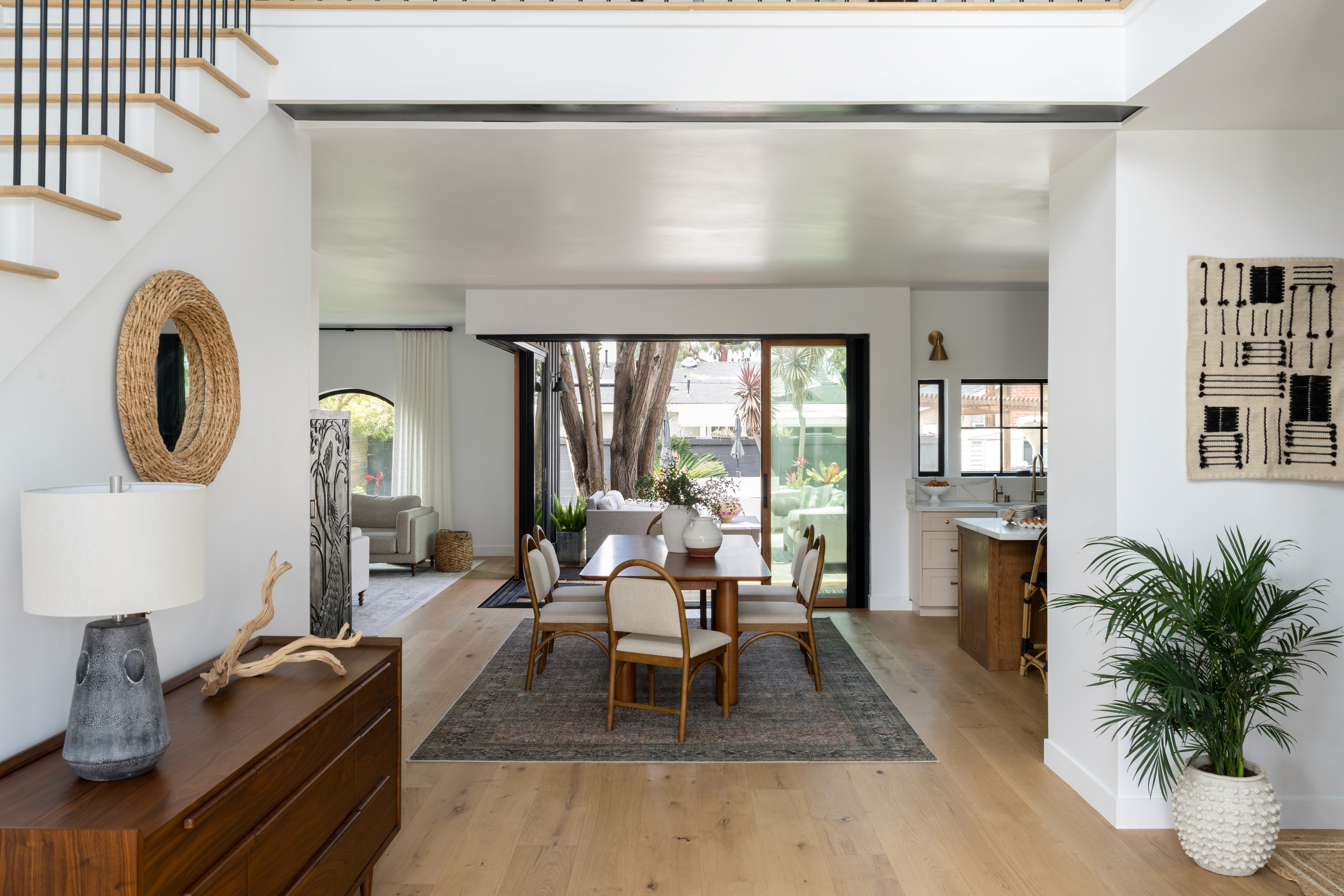 A welcoming entrance with a minimalist console table, decorative mirror, and soft lighting. The space is accented with a textured rug and hints of greenery, giving a fresh, inviting feel by Jubilee Interiors in Lakewood, California