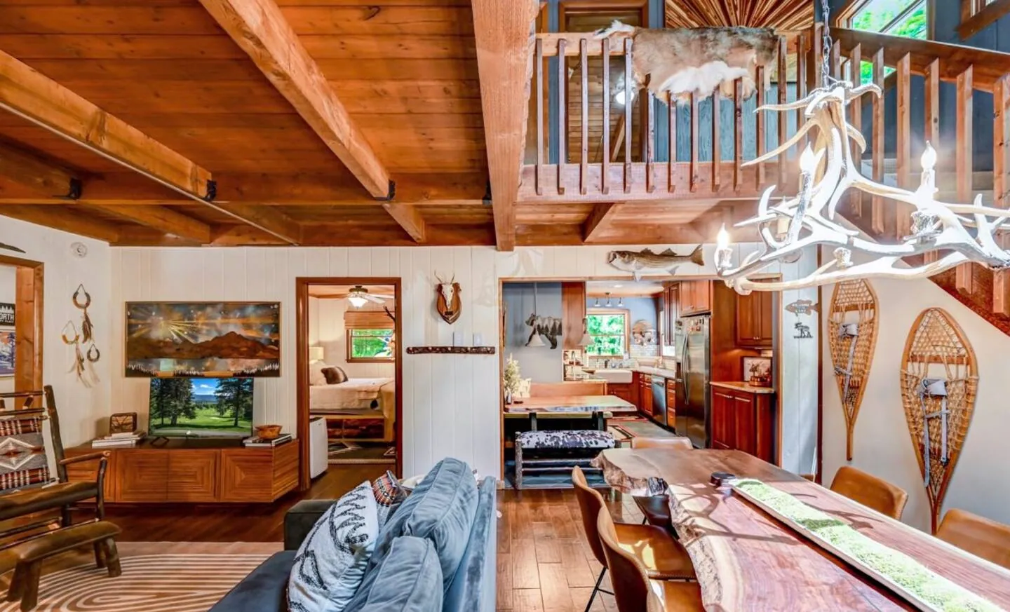 Dining table and living room under the loft with antler chandelier at Mountain MAMA