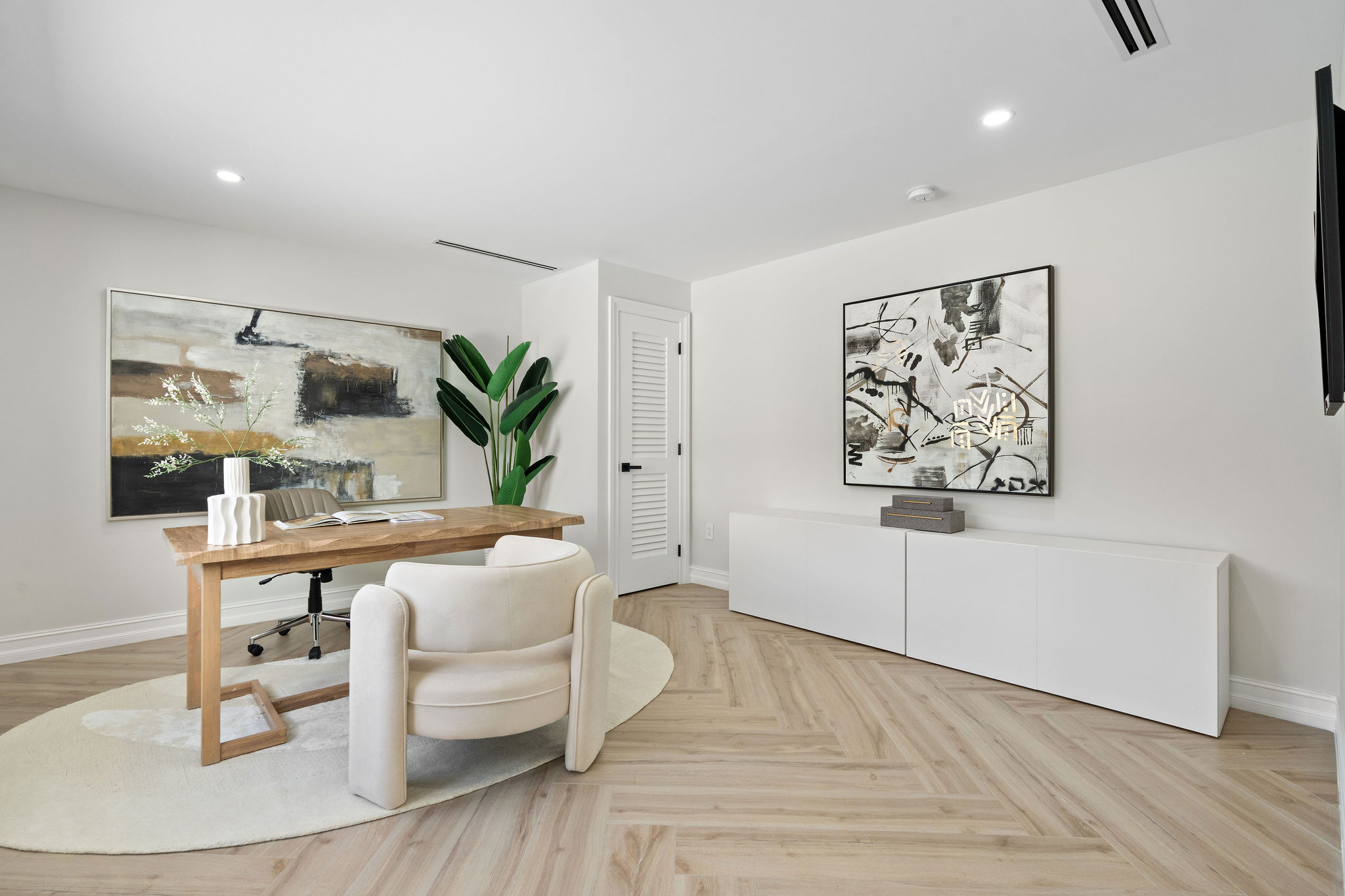 Modern home office with desk, chair, artwork and minimalist white credenza.
