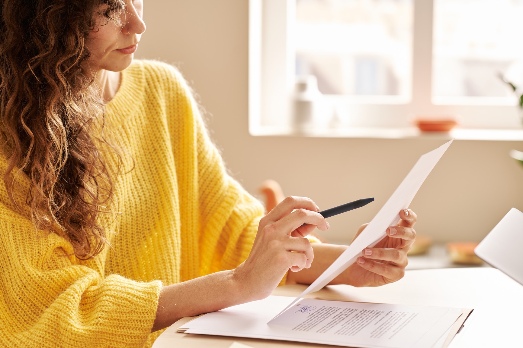 A woman in yellow looking at a sheet of paper