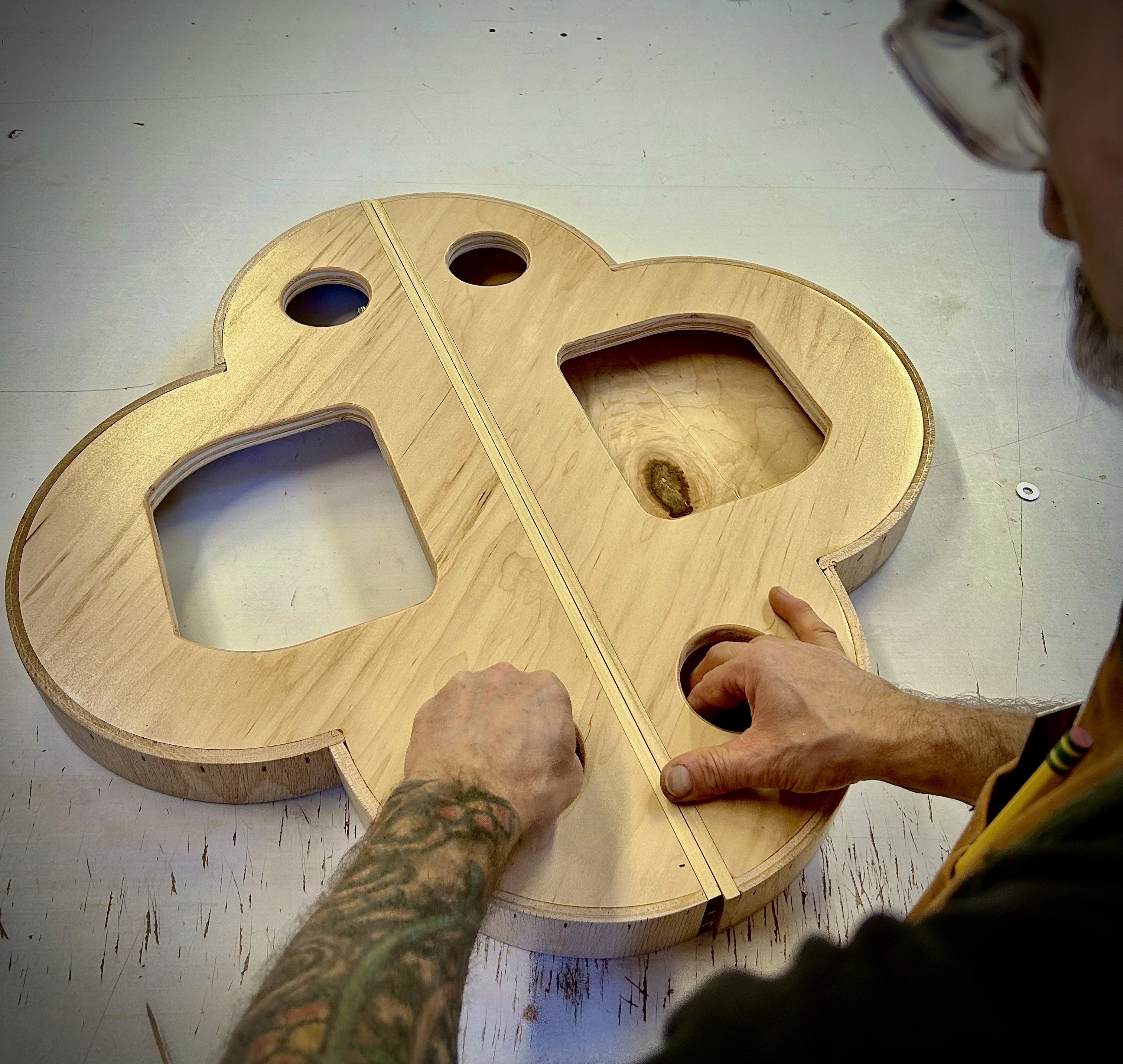 Woodworker works on the back of a custom fine art painting panel in the shape of a quatrefoil
