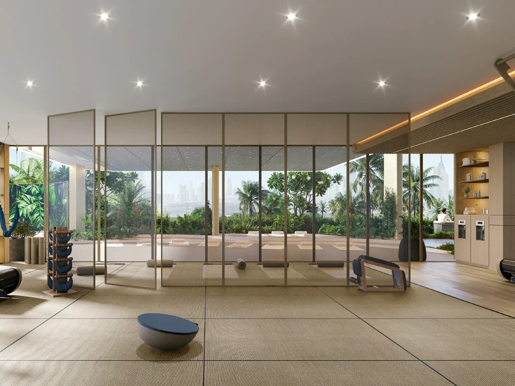A modern fitness room at Arka Enclave featuring a large glass wall, allowing natural light to illuminate the space.