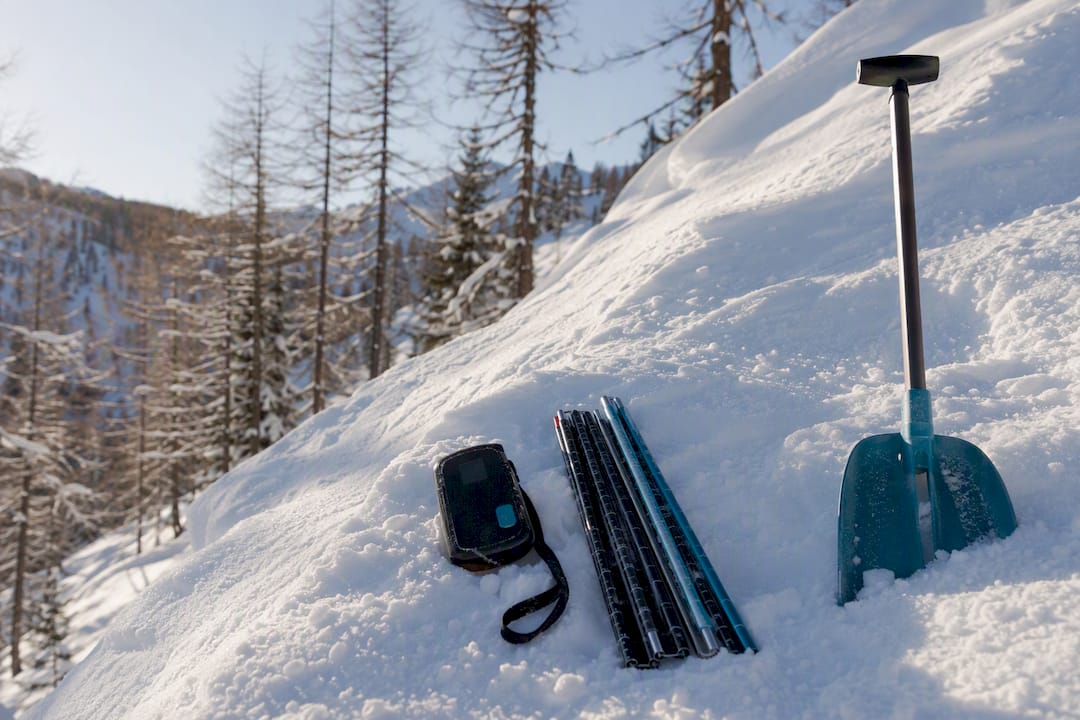 Avalanche transceiver, probe and shovel arranged on snow