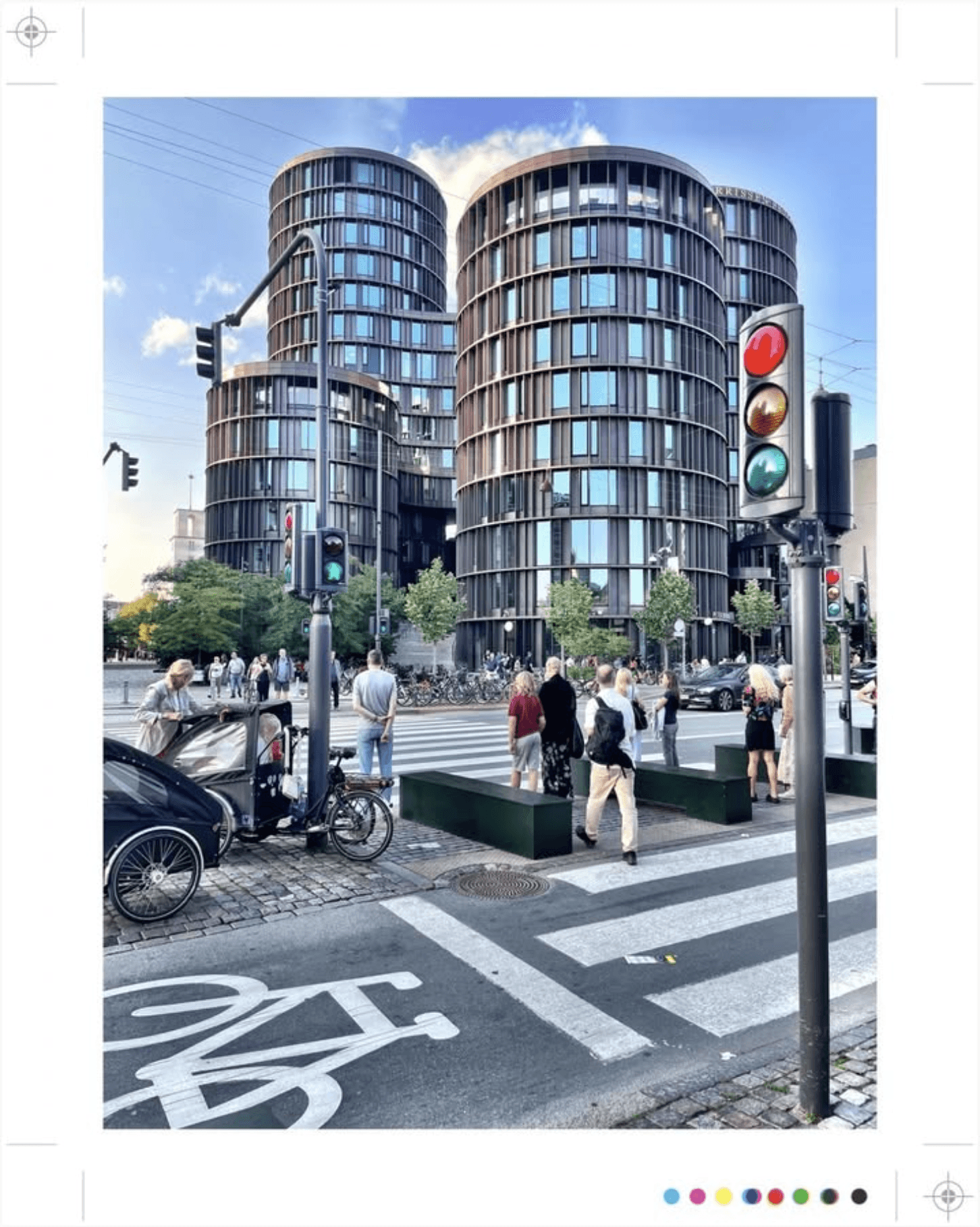 Rond gebouw in stad, voetgangers bij zebrapad, fietspad en verkeerslichten.