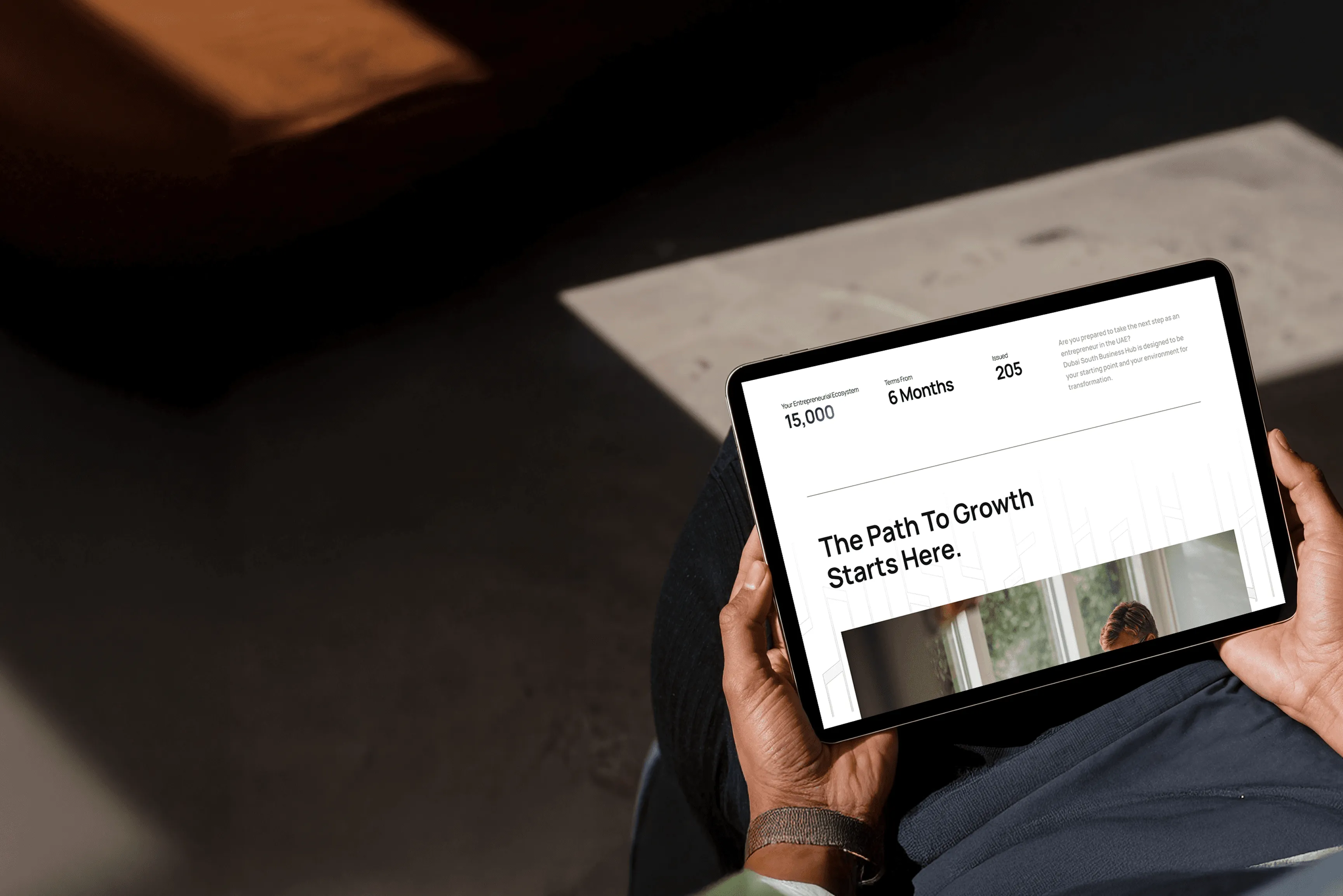 Dubai South Business Hub Free Zone -Person holding a tablet with the text "The Path To Growth Starts Here" on the screen.