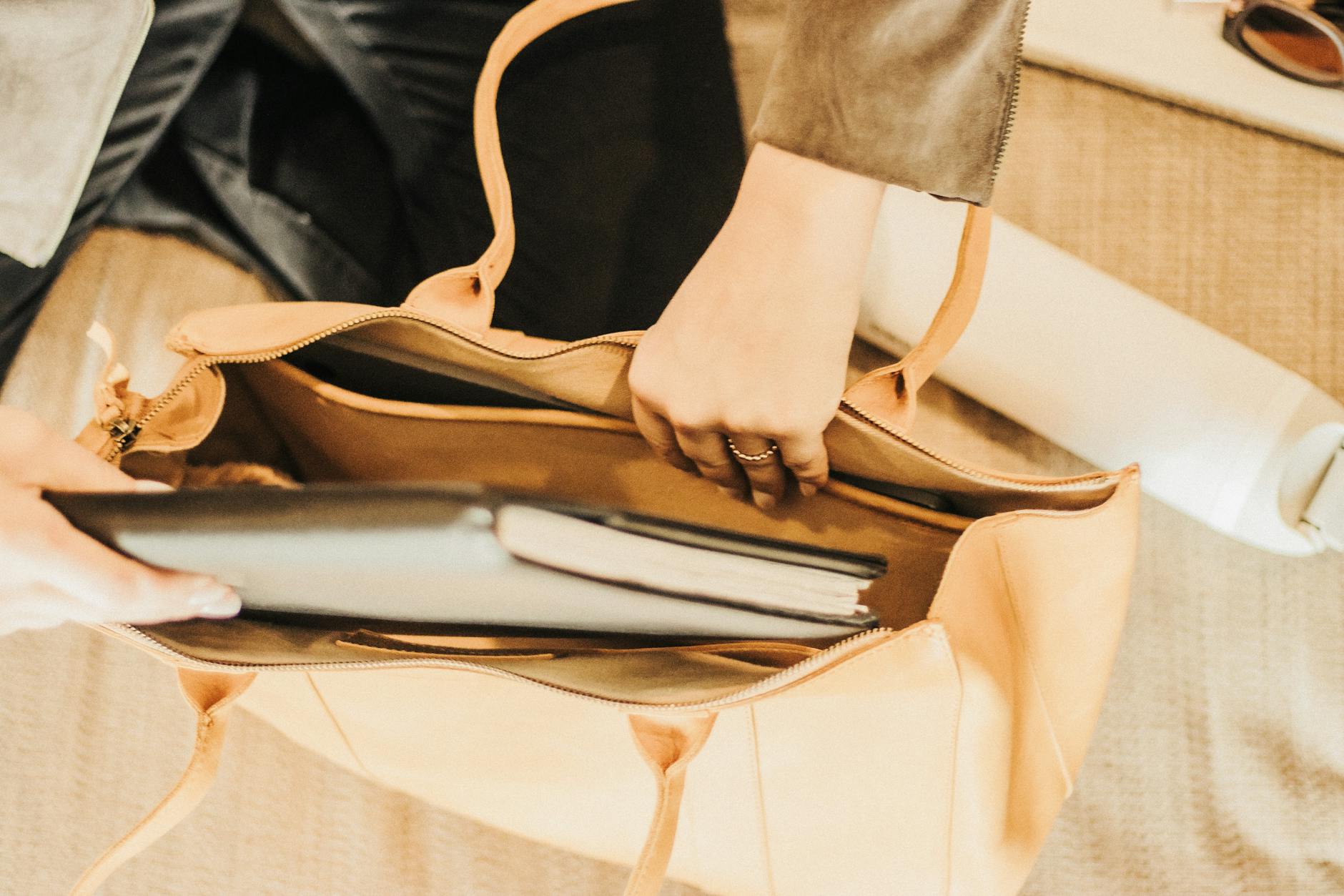 An elegant leather tote bag containing a laptop and notebook, perfect for travel or business use.