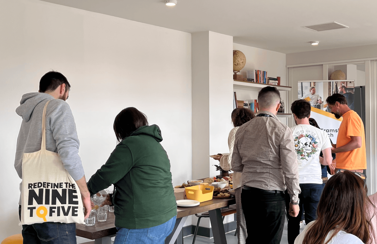 People serving food from a table in an art gallery.