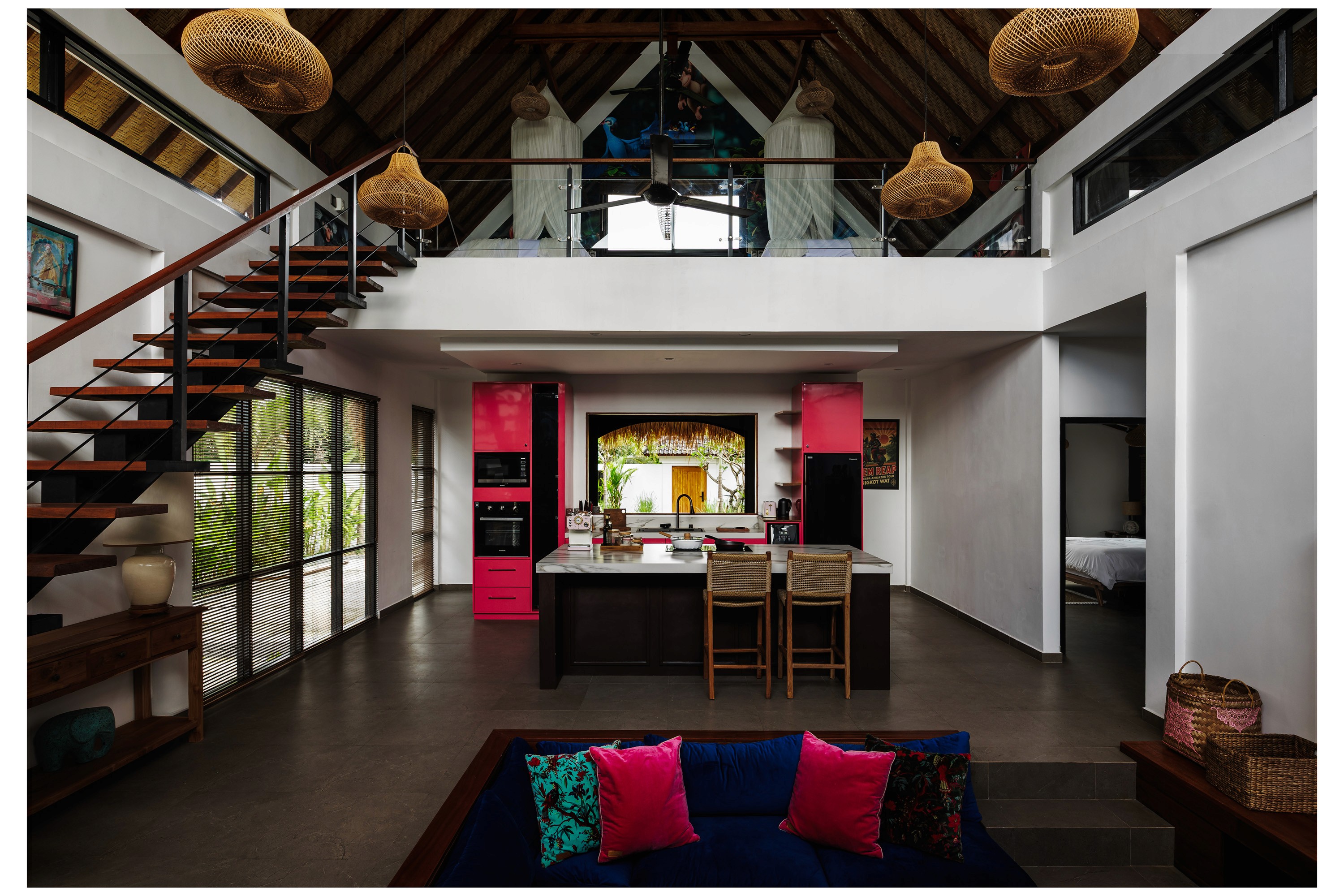 Open-plan living area with exposed roof beams, modern kitchen, and colorful tropical decor.