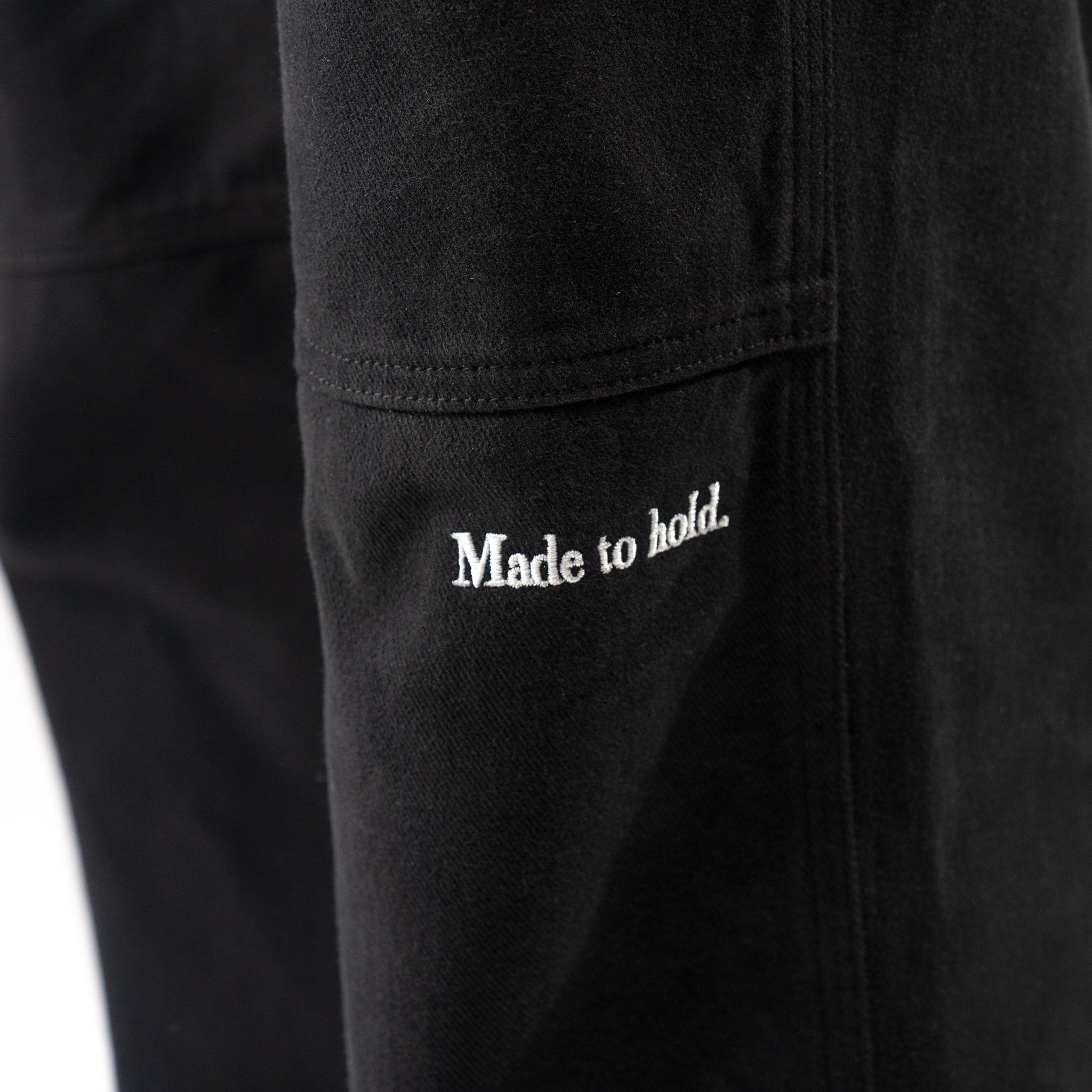 Black pants with 'Made to hold.' text on a white background