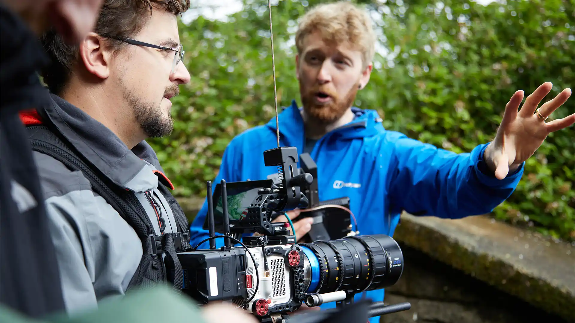 Group of presenters speaking on camera during a Microsoft live broadcast, filmed against branded event graphics.