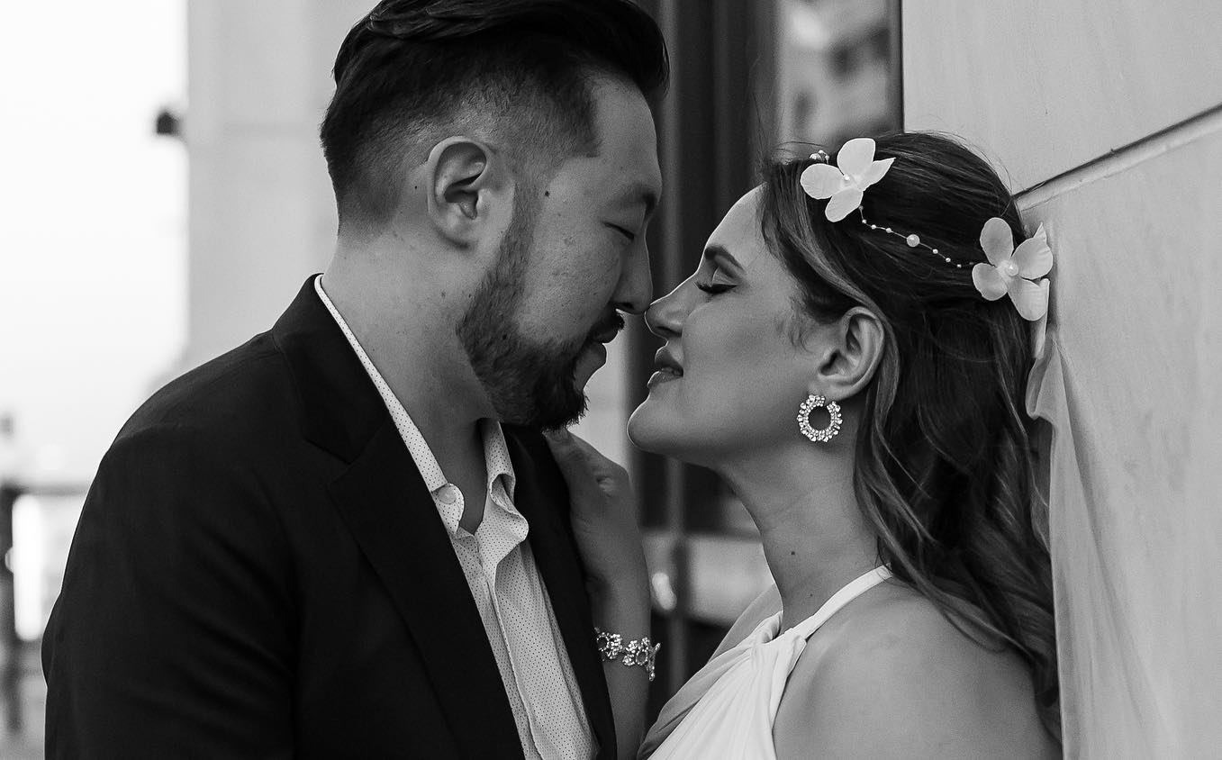 A bride and groom sharing a loving kiss in front of a building. Made with SEO keywords in mind to enhance visibility and crafted using Framer for an exceptional design.