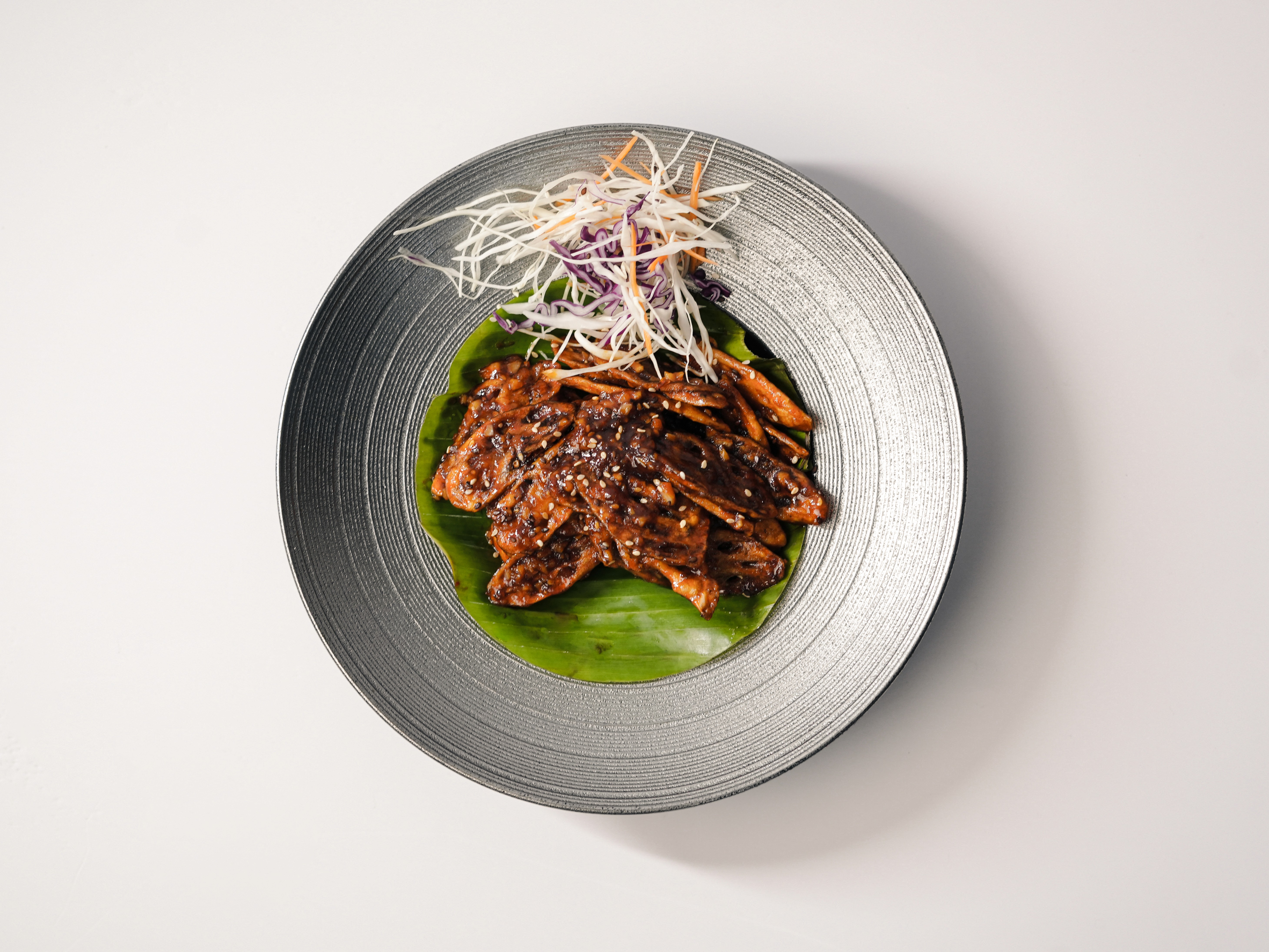 Person with a mustache wearing a black t-shirt carrying a tall stack of pizza boxes inside a dimly lit bar or restaurant.