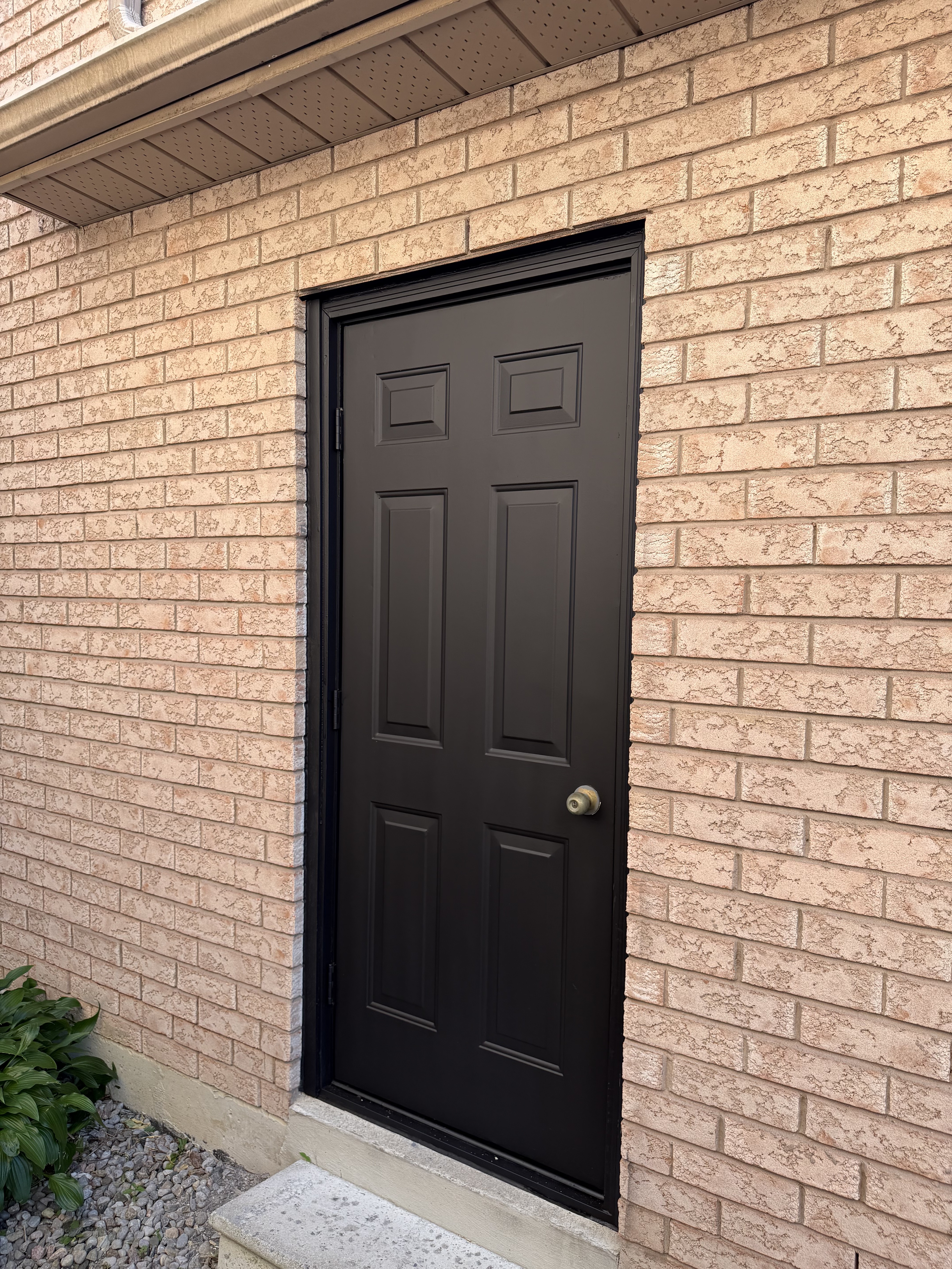 Black panel entry door with white trim against red brick