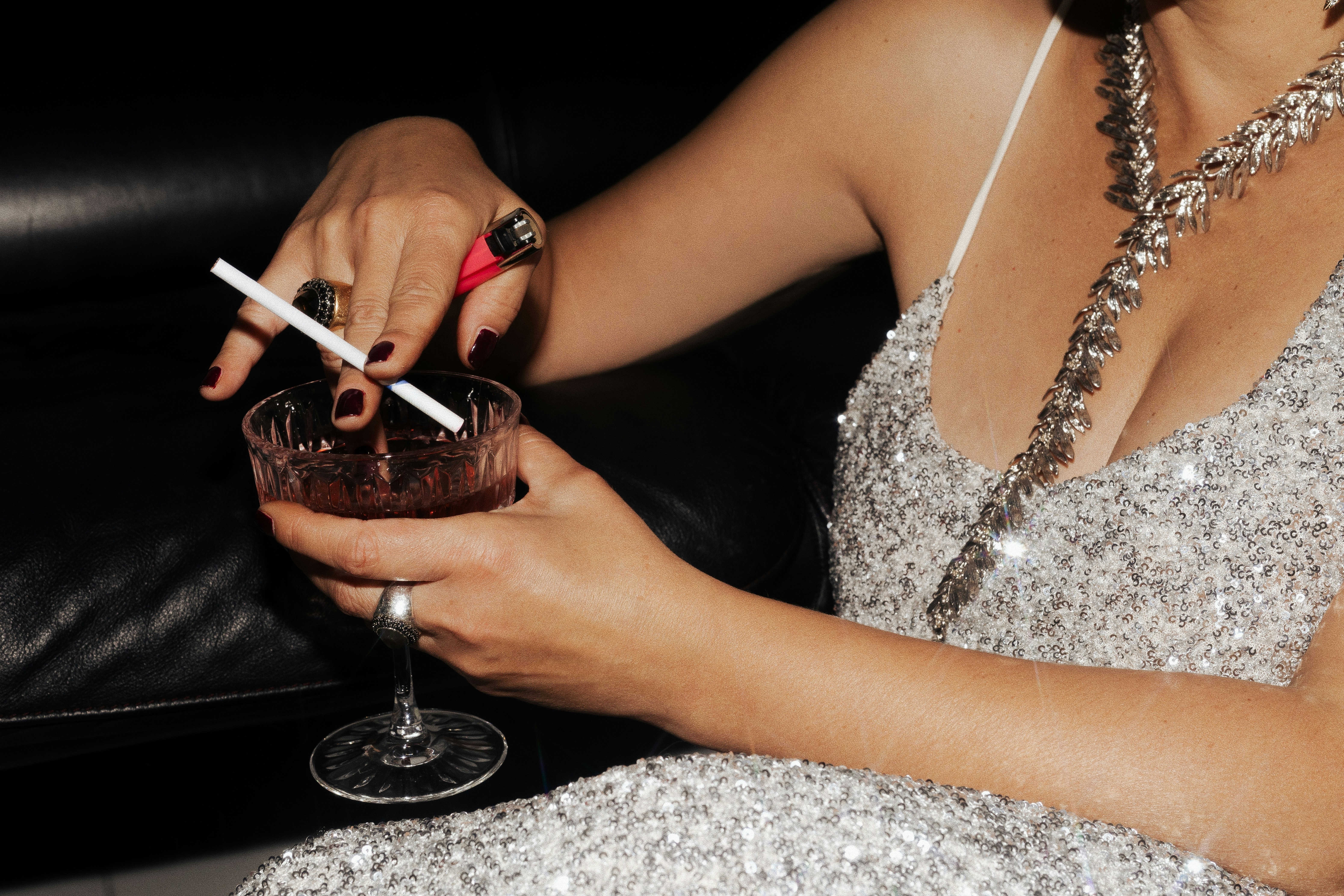 Close up detail of hands holding a cocktail and cigarette, highlighting the refined and intentional aesthetic of Angel’s stage identity.