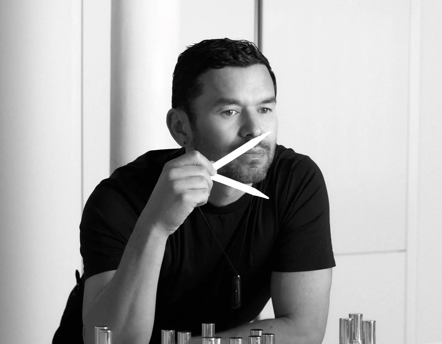 Founder Josh Máno Gilbertson at a perfumery lab table with sample bottles