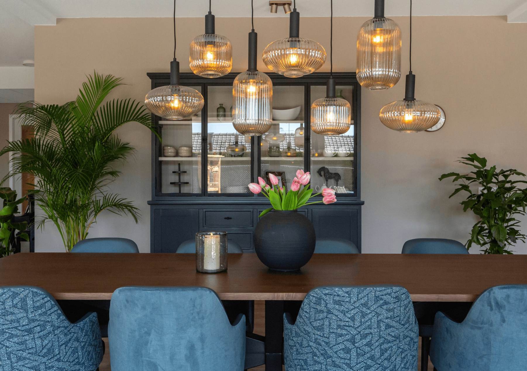 eettafel met blauwe stoelen en geribbelde hanglampen